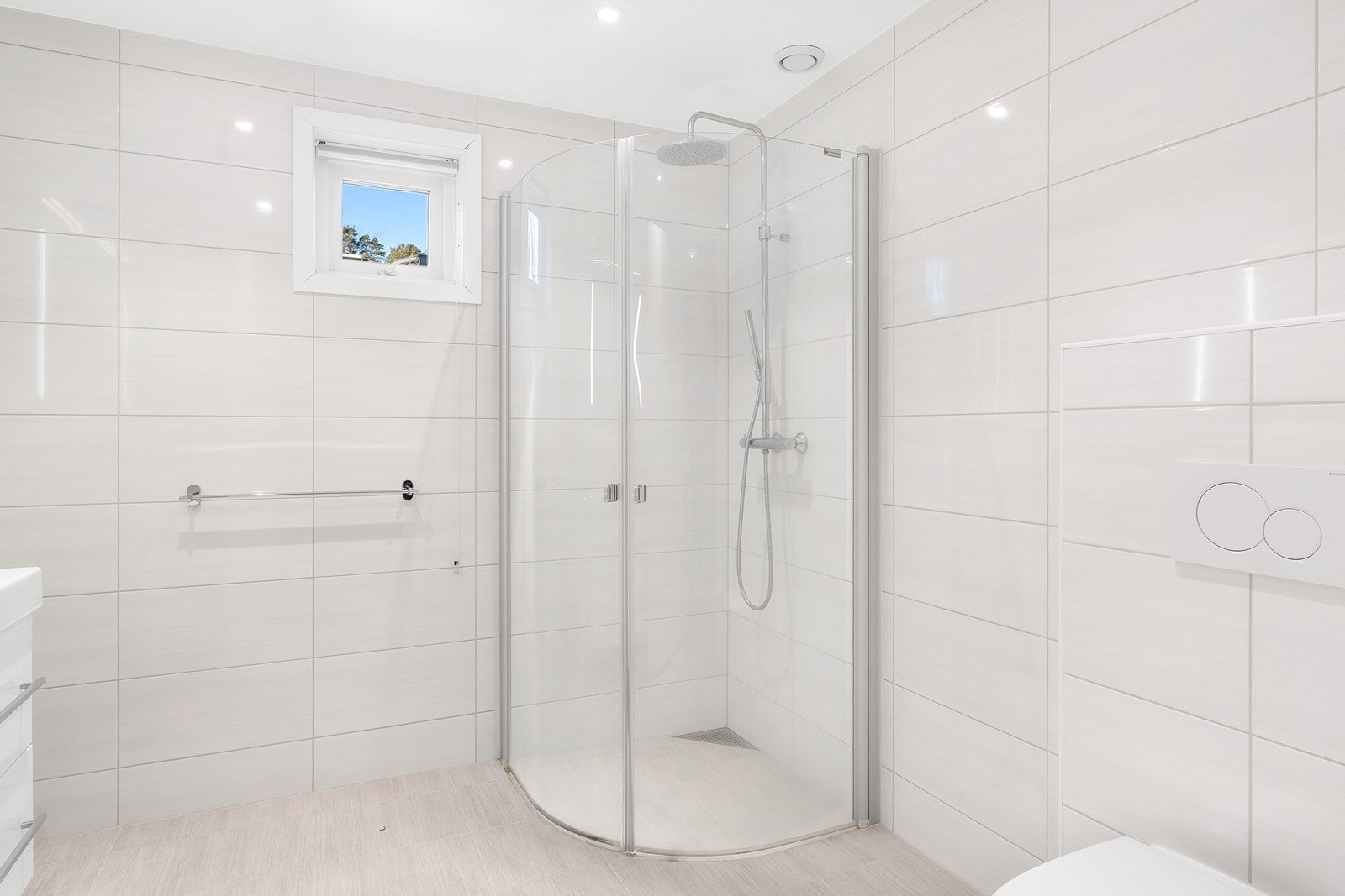 Badet er innredet med vegghengt toalett, baderomsmøbler med servant og innfeltbare dusjdører. Galleribilde