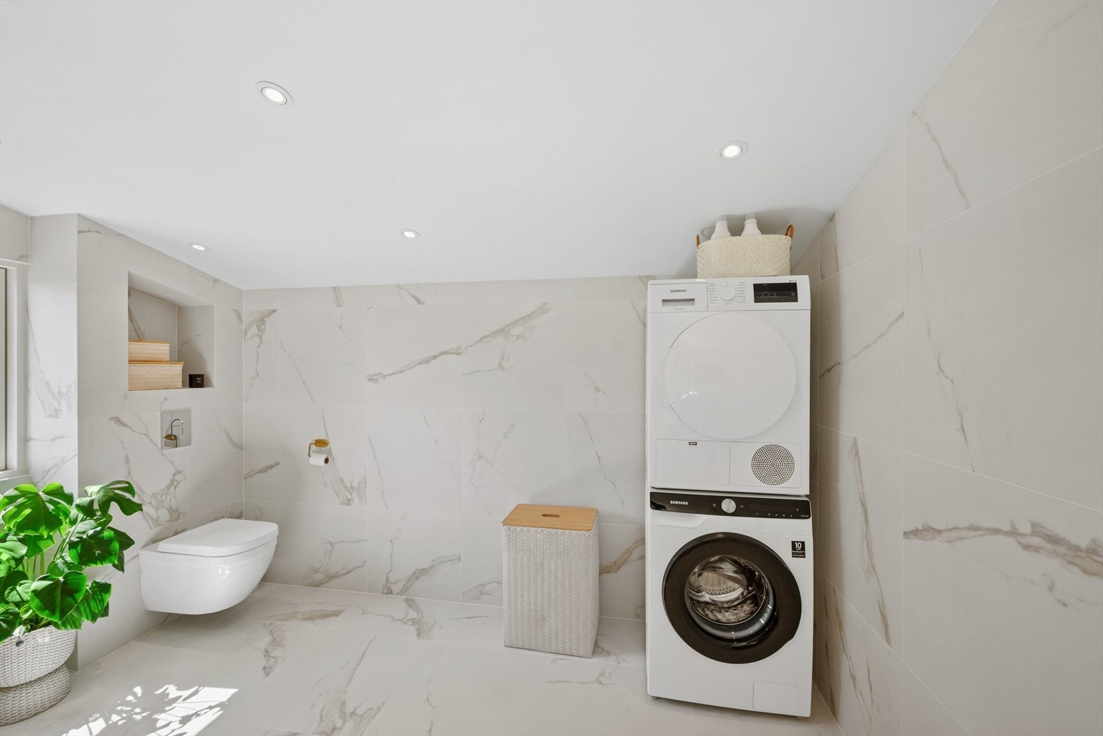 Baderommet har et veggfestet klosett med innebygget sisterne, en dusj på gulv med innfellbare dusjvegger i herdet glass, og en dobbel servant i helstøpt plate med tilhørende skuffer under. Galleribilde