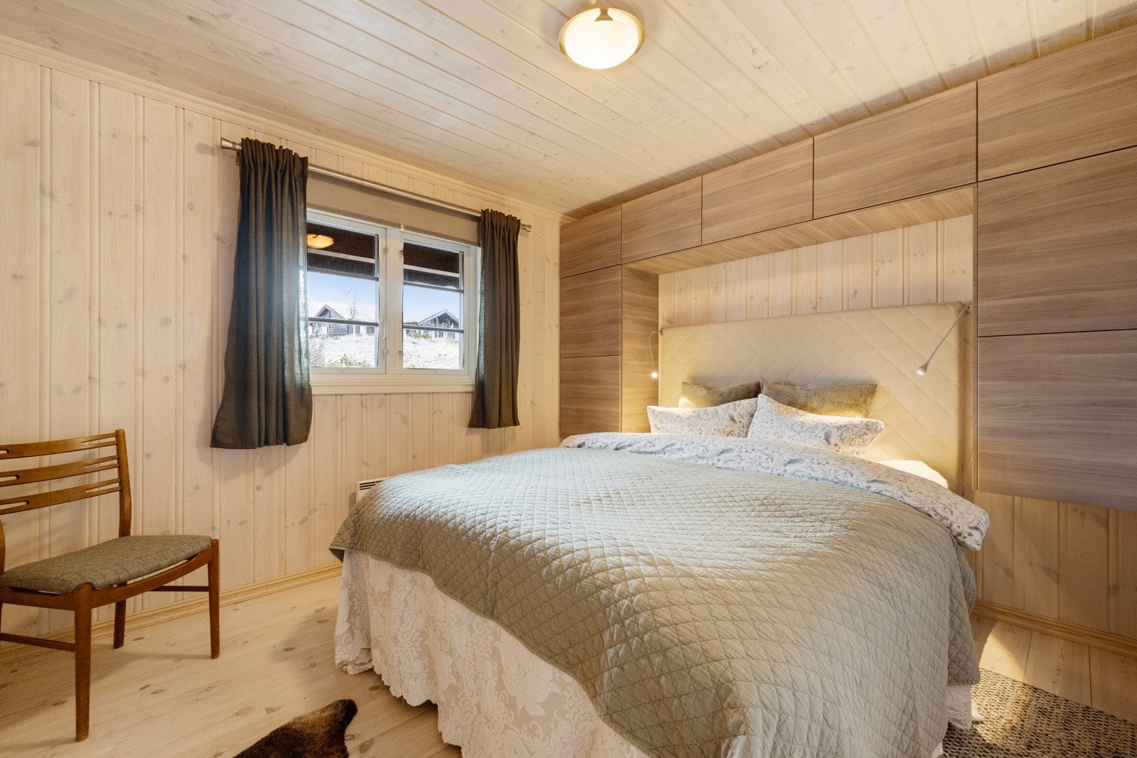 De plassbygde skapene starter i hodeputehøyde på hver side av sengen og fortsetter over sengen, noe som gir både et helhetlig uttrykk og god oppbevaringsplass. Galleribilde