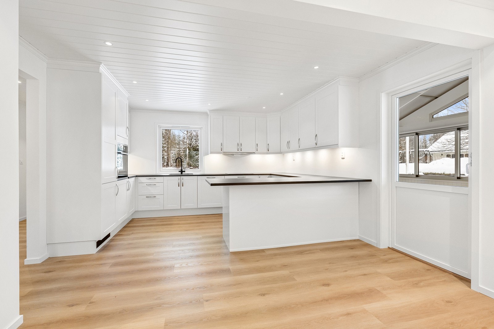 Nytt kjøkken fra 2024-2025 med hvite, profilerte fronter, laminert benkeplate og et benkehjørneskap med karusellfunksjon. Galleribilde