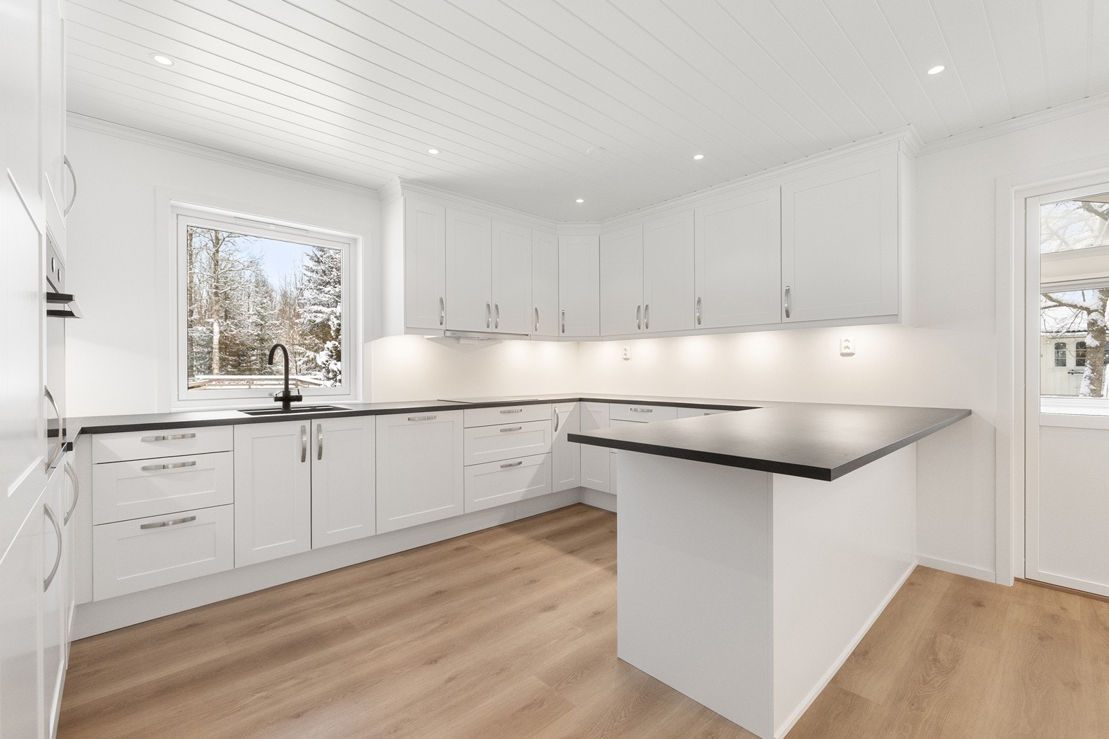 Vinkelformet kjøkkeninnredning med mye skap- og benkeplass, samt praktisk barløsning. Galleribilde