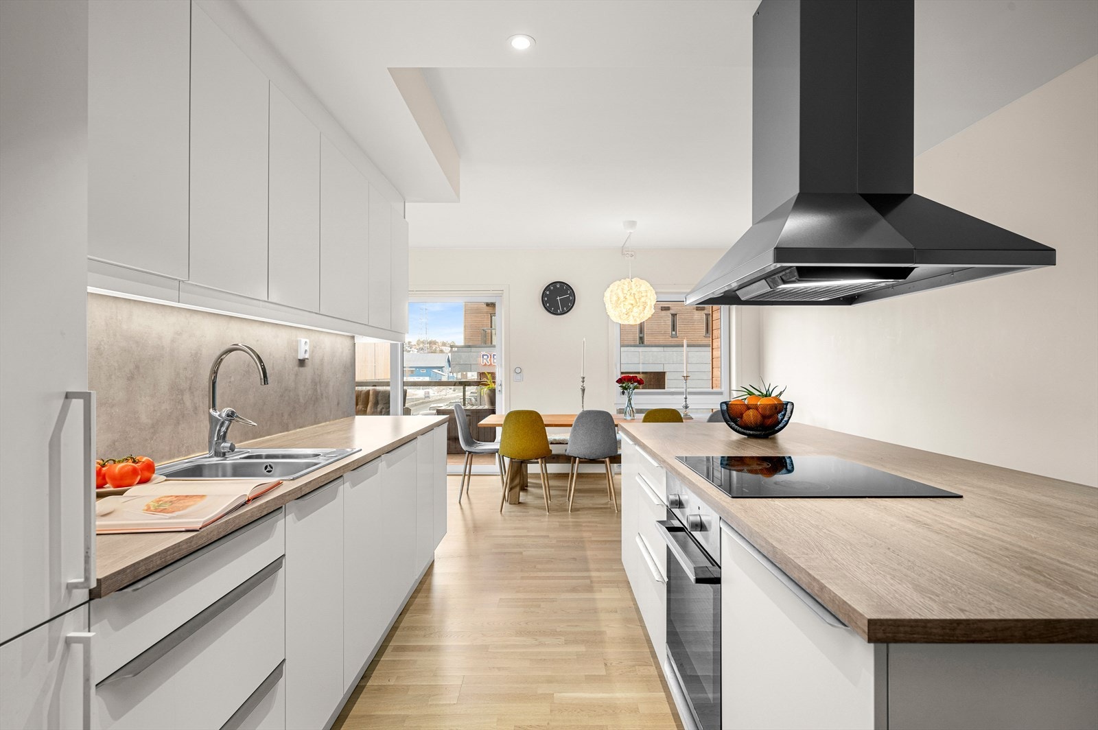 Stilren kjøkkeninnredning med slette fronter og benkeplate i laminat. Det er integrert platetopp, stekeovn, oppvaskmaskin og kombinert kjøl og fryseskap. Galleribilde