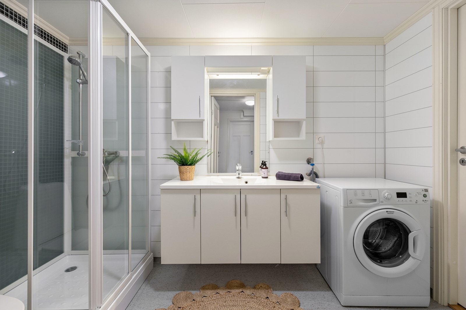 Badet er eit kombinert bad og vaskerom med golvbelegg med oppkant, baderomsplater på veggar og tak-ess i himling. Galleribilde