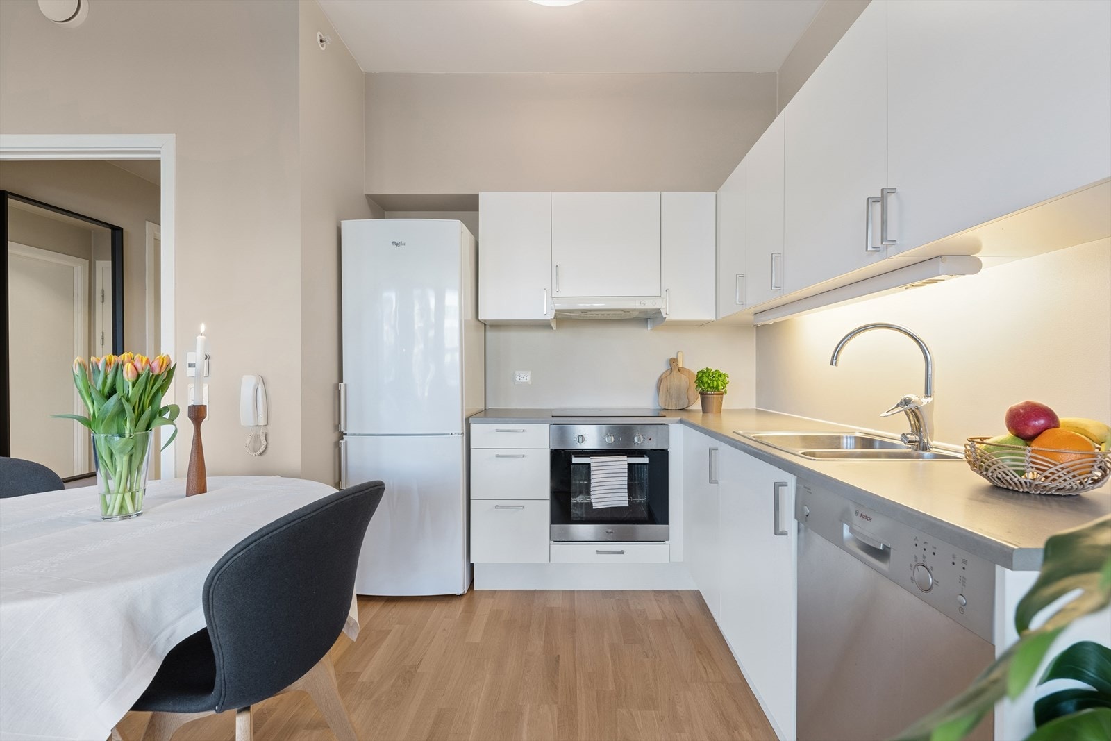 Kjøkkenet er av hvite slette fronter med god plass til oppbevaring i over- og underskap Galleribilde