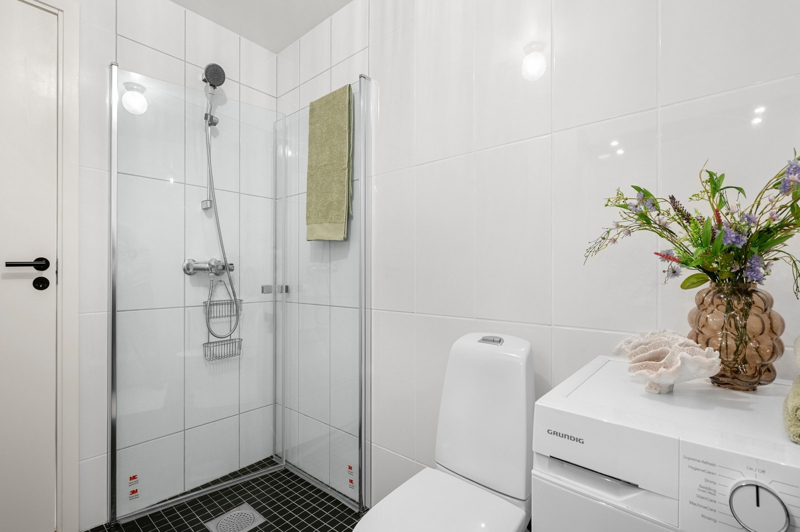 Flott flislagt bad på 5 kvm med opplegg for vaskemaskin, innfellbare dusjdører, wc og servantskap. Galleribilde