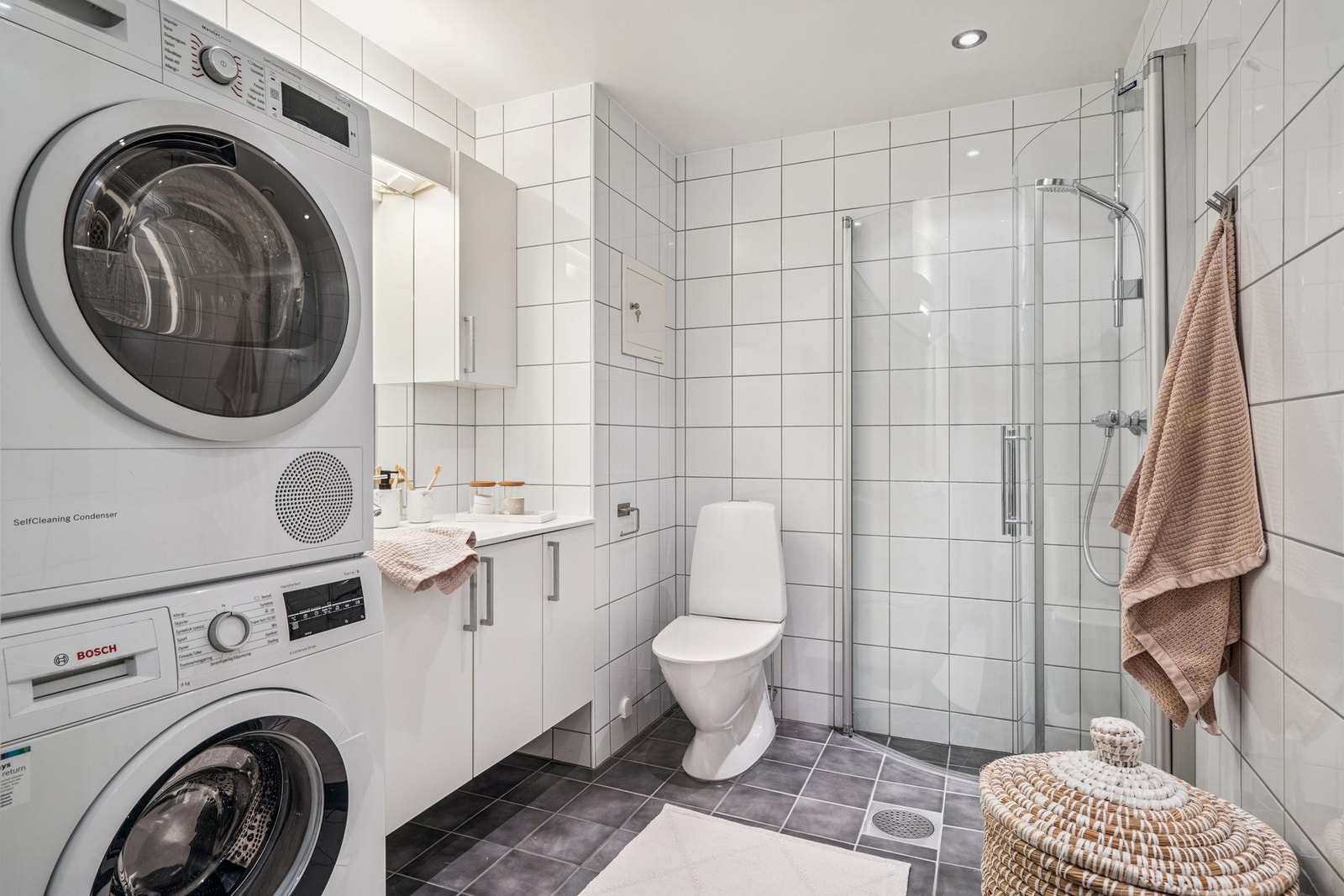 bad med flislagte overflater og praktisk opplegg for vaskemaskin og tørketrommel. Galleribilde