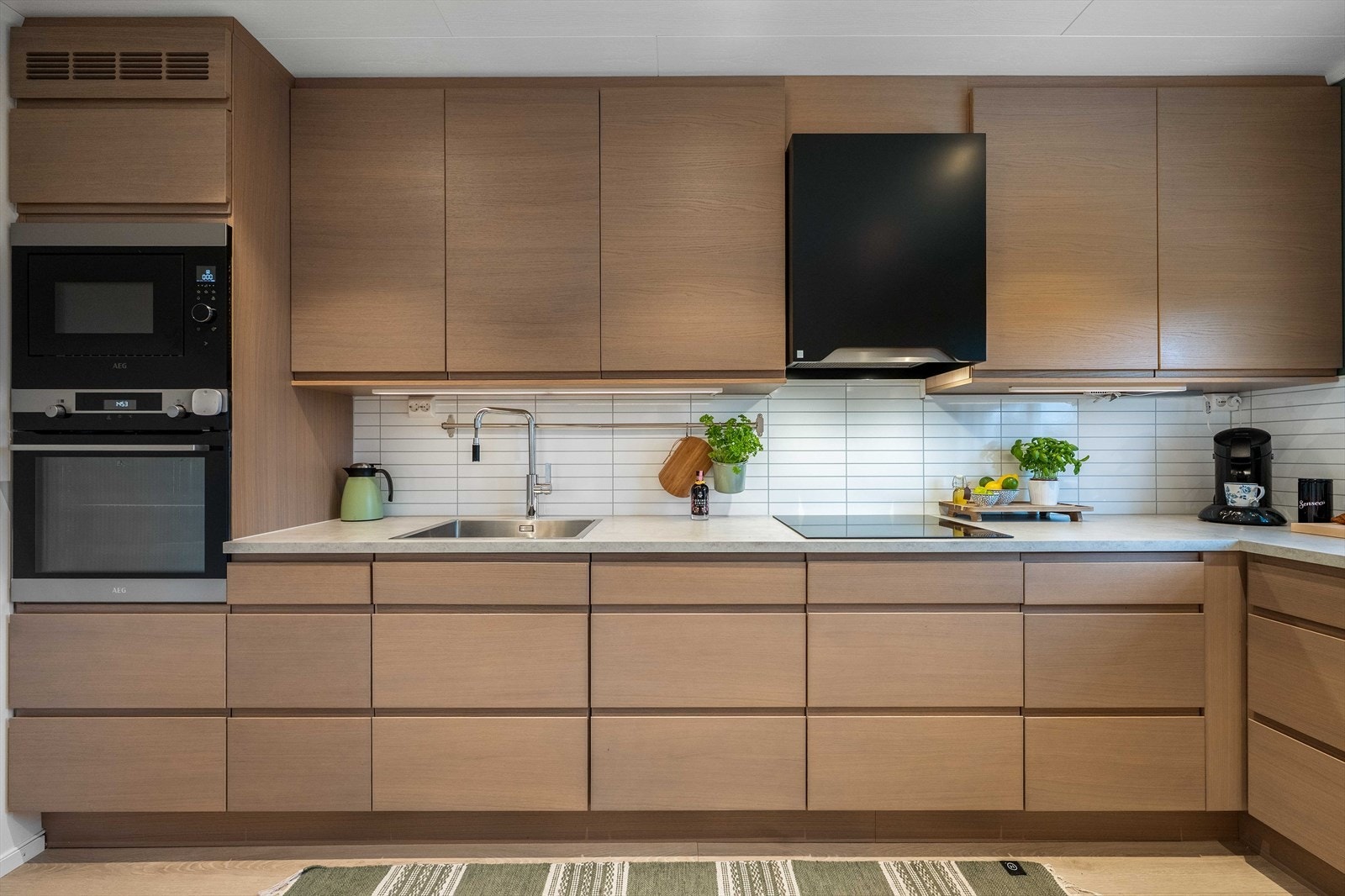 Det er rikelig med både skap- og benkeplass, noe som gir en svært funksjonell og effektiv arbeidssone. Her ligger alt til rette for praktisk matlaging og smart organisering i hverdagen. Galleribilde