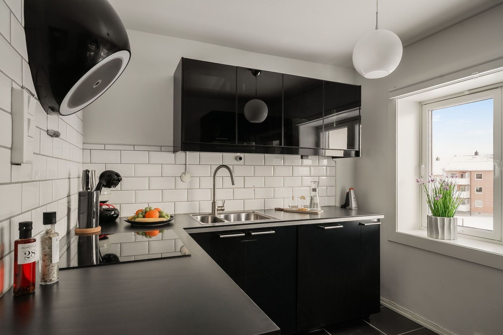 Stilrent og funksjonelt kjøkken med folierte skrog, slette sorte fronter, laminert benkeplate, hvite fliser og vindusflater som gir naturlig lys og et behagelig arbeidsmiljø. Galleribilde