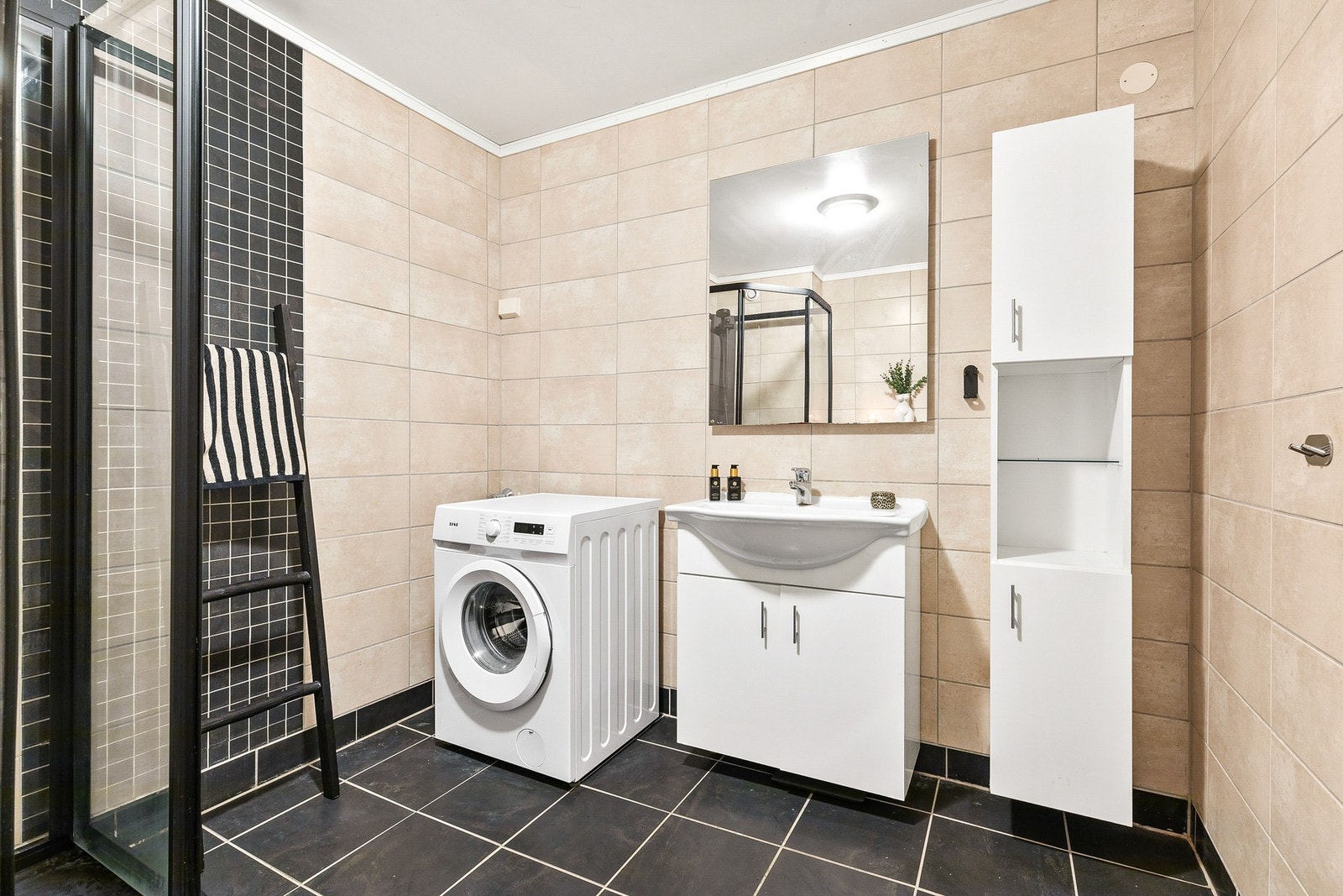 Rommet har innredning med nedfelt servant, veggmontert toalett, dusjkabinett og opplegg for vaskemaskin Galleribilde