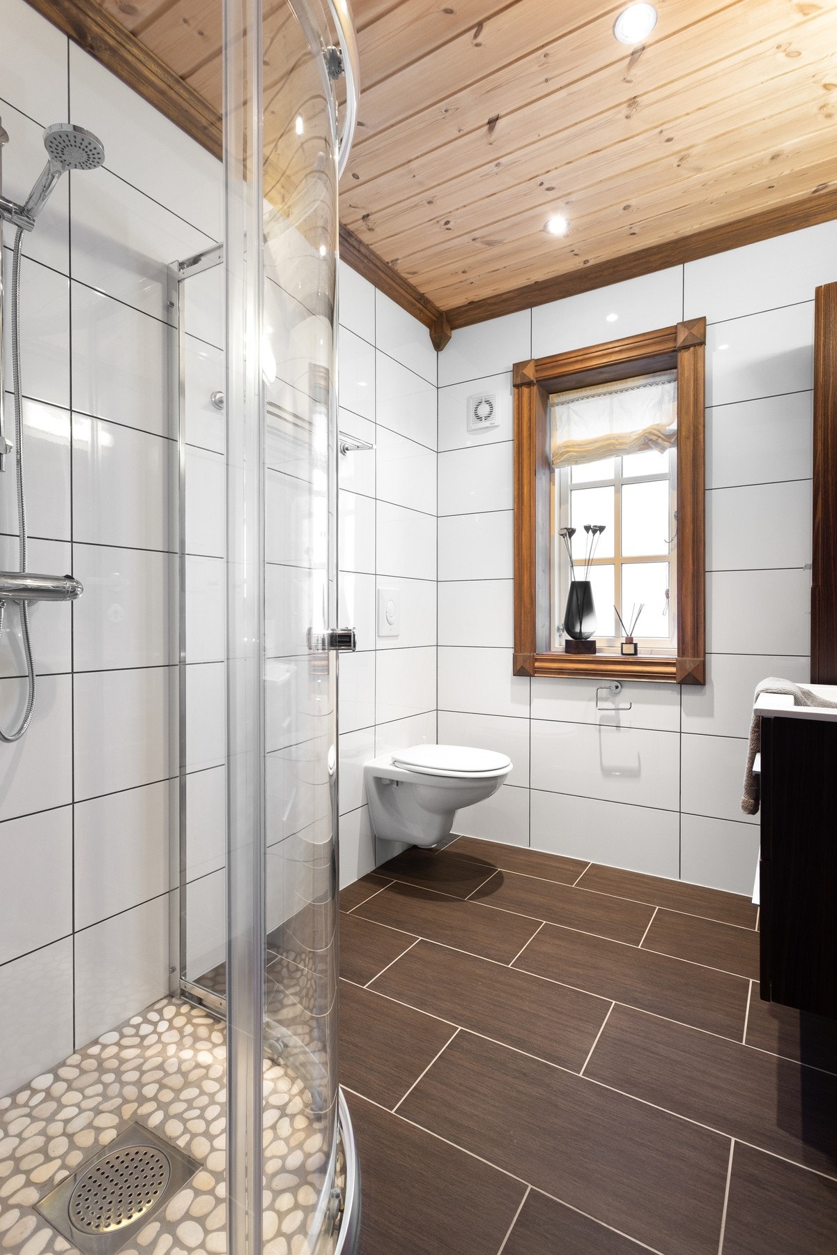 Baderom i 1.etasje med vegghengt toalett, dusjhjørne med glassdører og innredning med servant Galleribilde