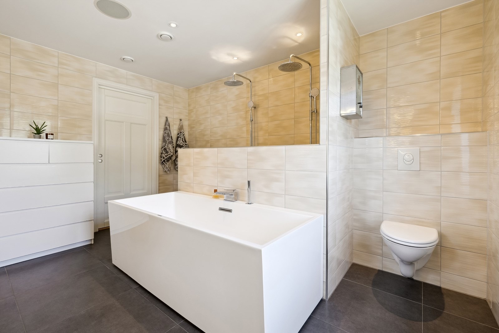 Flislagt bad i 2. etasje har gulvarme, vegghengt toalett, badekar, dobbeldusj i nisje og baderomsinnredning med servant. Praktisk klessjakt til vaskerom. Galleribilde