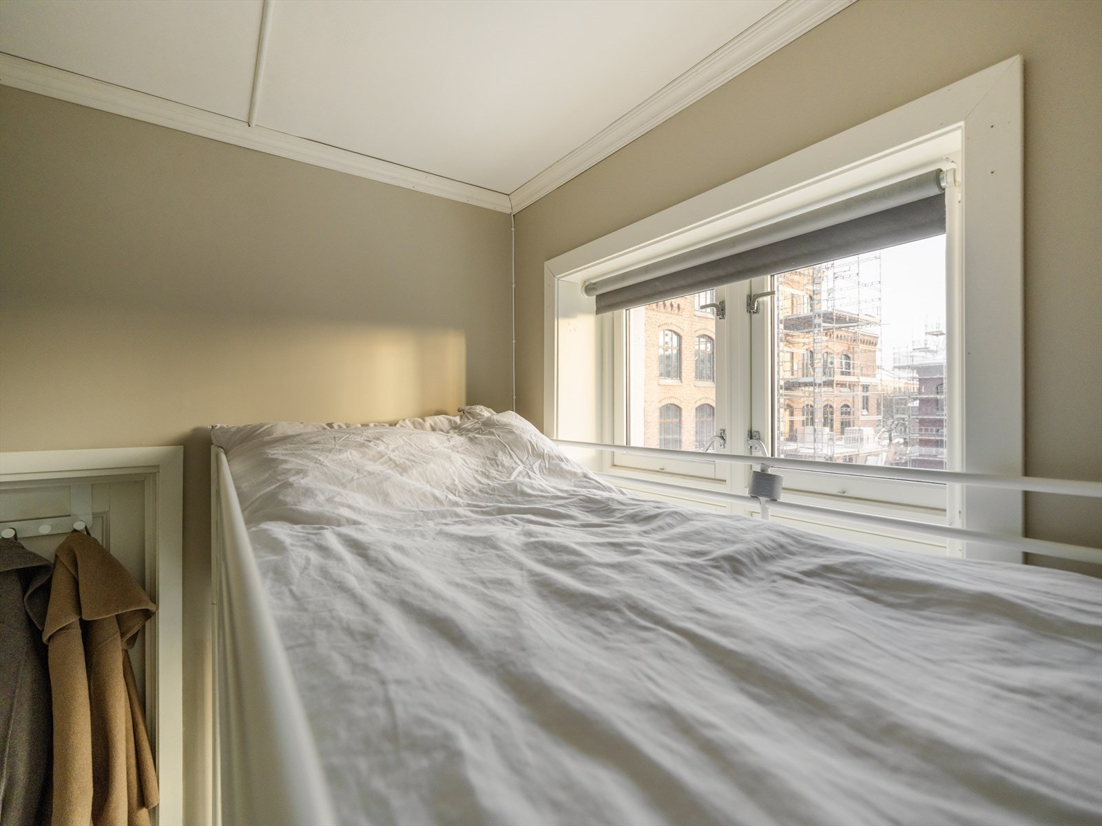 Soveplass med vindu gir lys inn i soveområdet og utsikt til nærliggende bygninger. Galleribilde