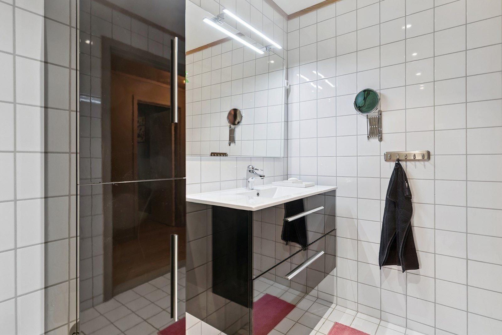 Flislagt bad i underetasjen med dusjhjørne med innfellbare dører og vegghengt servantskap. Galleribilde