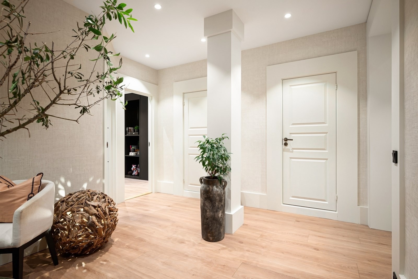 Romslig og lys hall med bruk av downlights og lekker tapet i en lun farge. Galleribilde