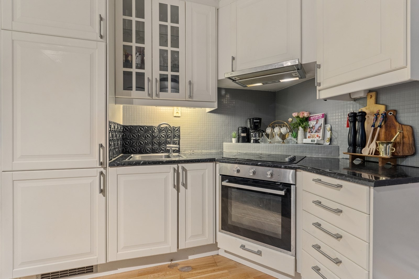 Benkeplaten er i laminat og har nedfelt oppvaskkum med tilhørende kjøkkenkran. Over benk er det flislagt vegg og belysning under overskapene. Galleribilde