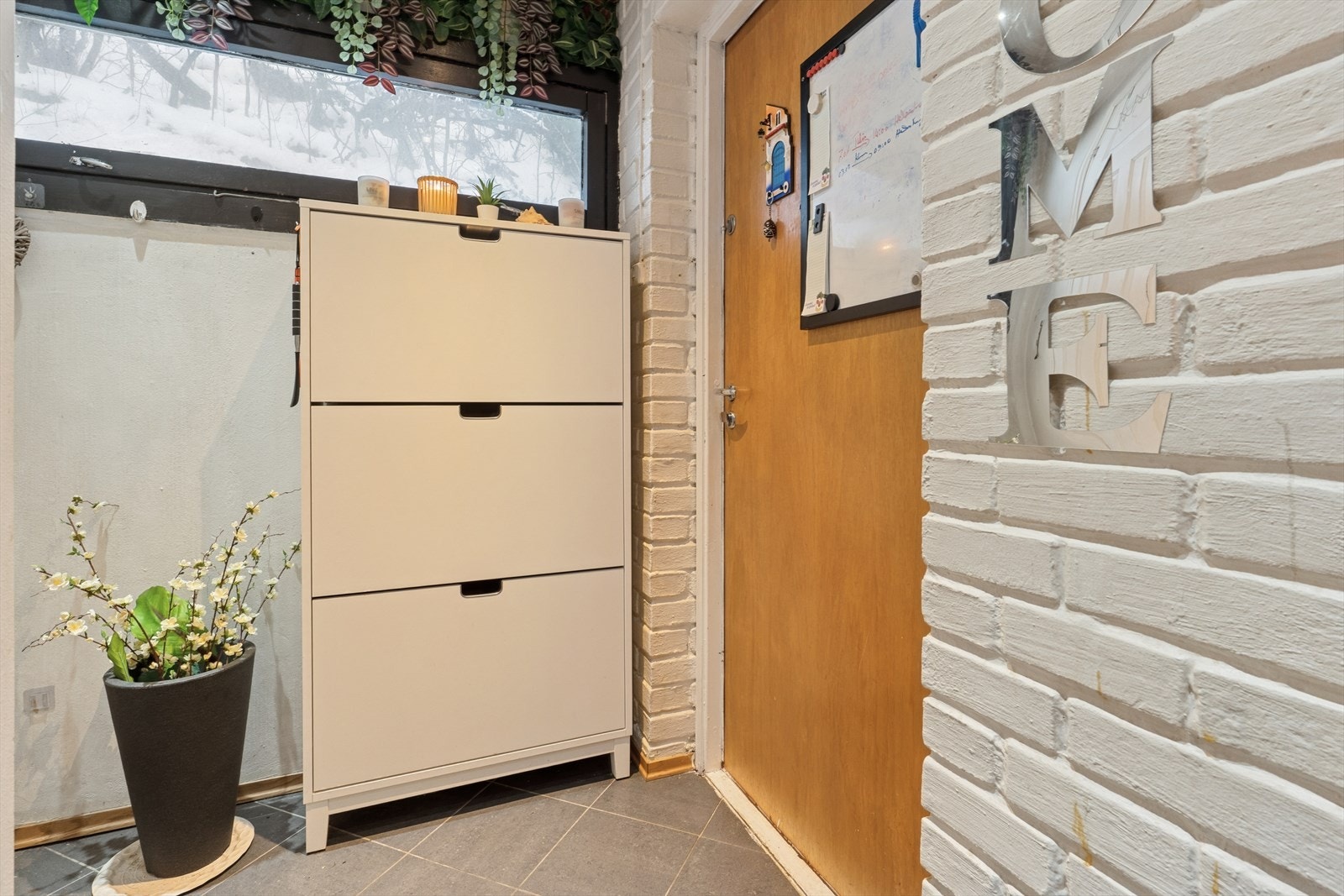 Entré med flislagt gulv og enkelte vegger i malt teglstein, som gir rommet et rustikt preg. Galleribilde