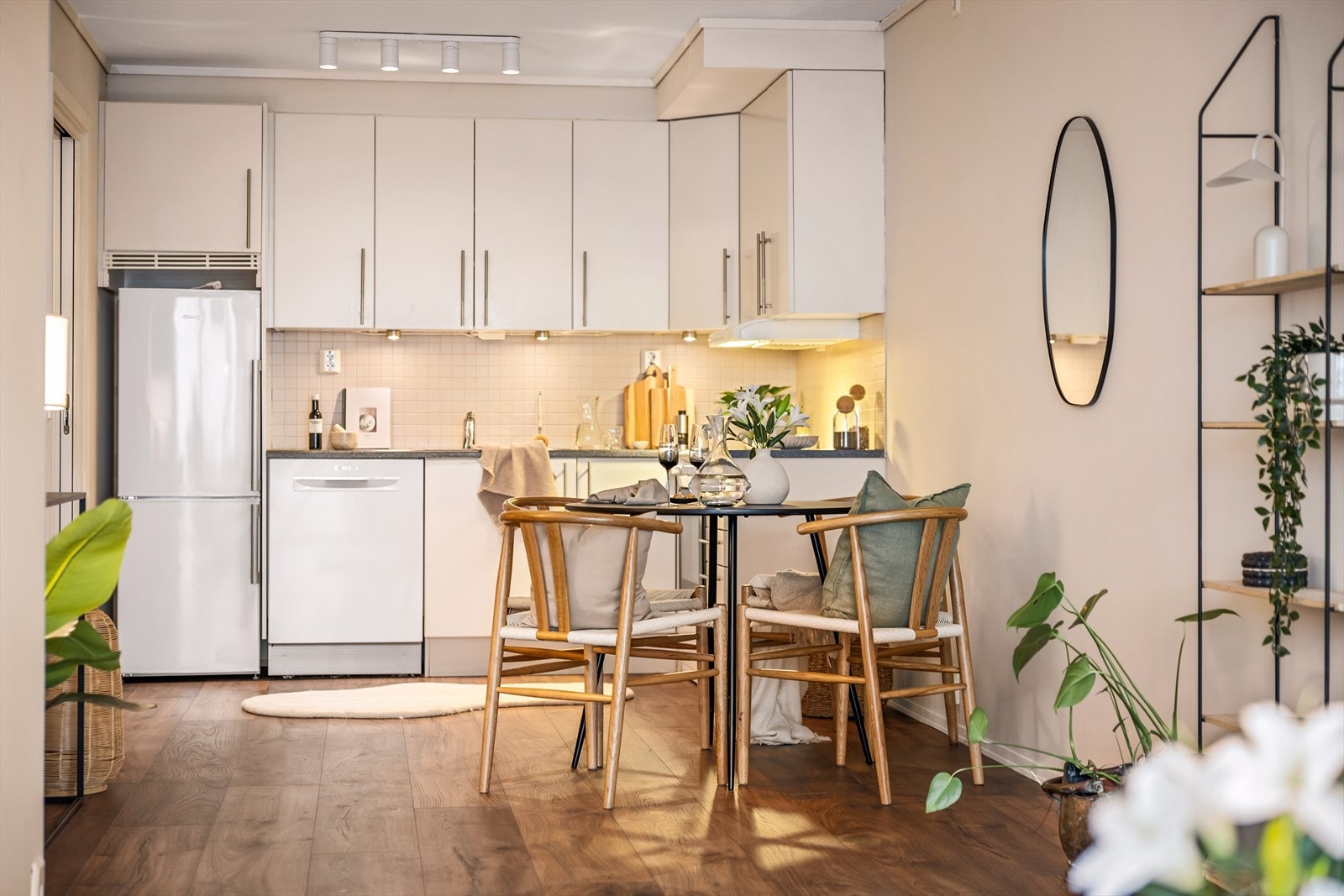 Flott kjøkken med innredning i slett lys utførelse med takhøye skap, grå laminat benkeplate med fliser over. Galleribilde