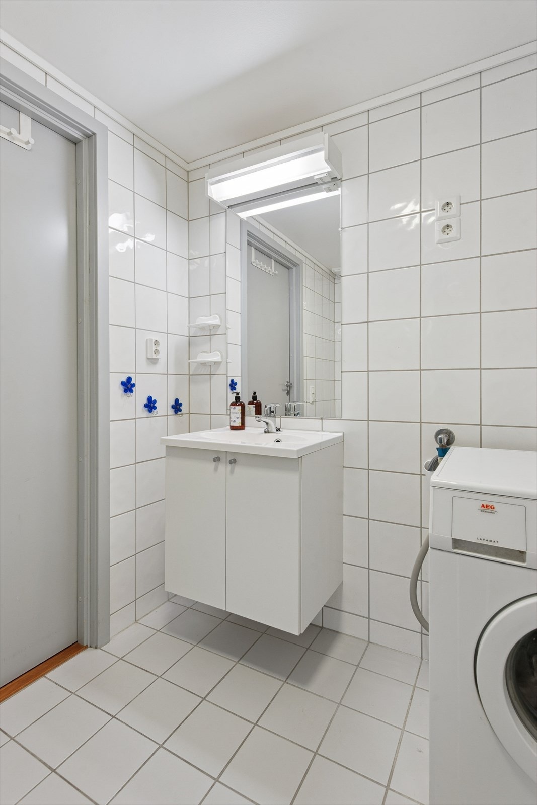 Badet er helfliset med hvite fliser på vegger og gulv. Galleribilde