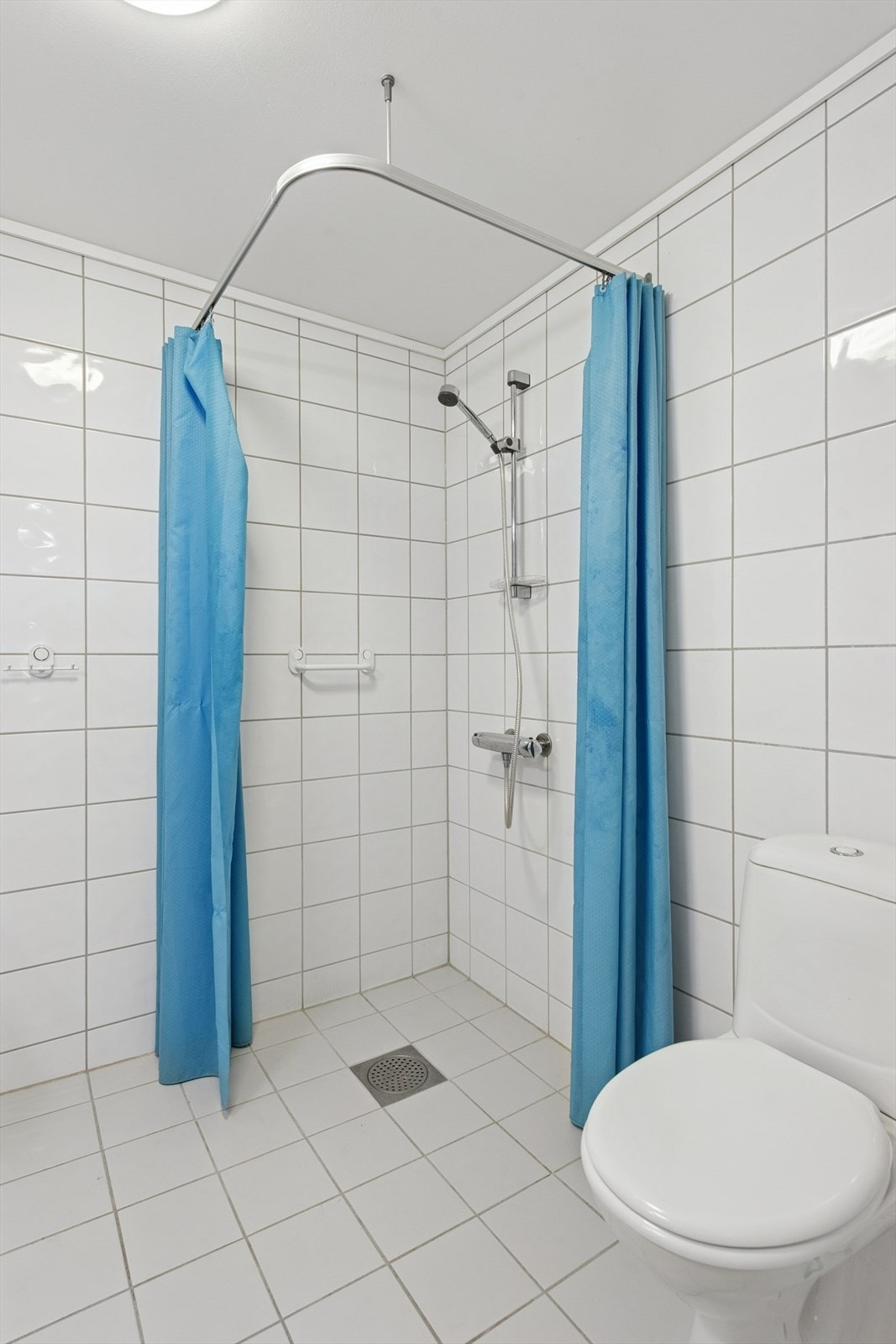 Badet er utstyrt med dusjhjørne, vegghengt servant og toalett. Galleribilde