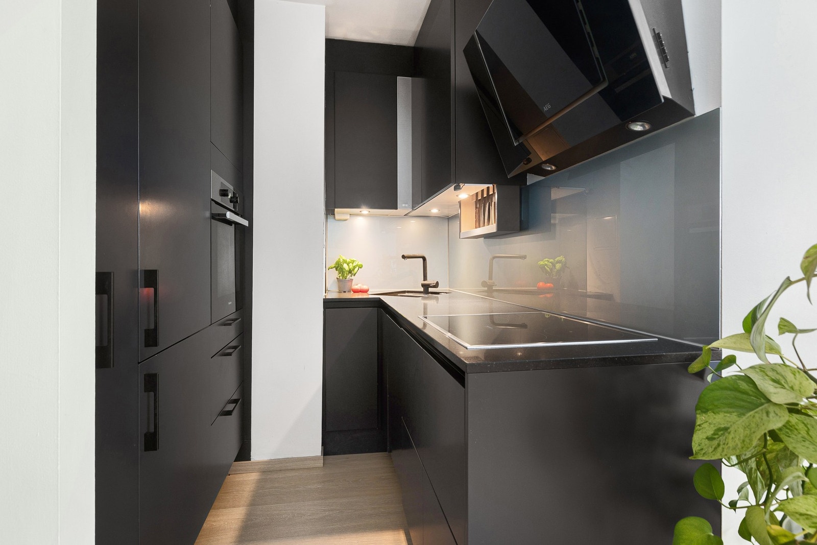 Lekker kjøkkeninnredning fra 2018 med stilrene overflater med slette sorte overflater og benkeplate i stein. Galleribilde