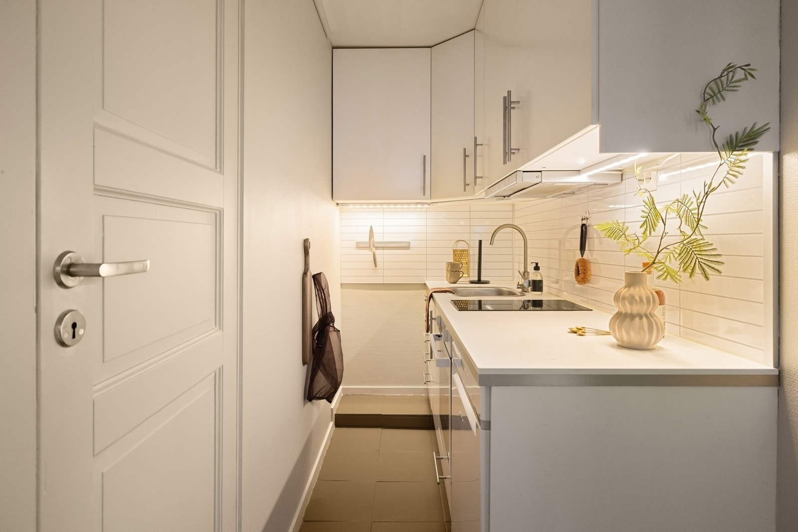 Kjøkkeninnredning fra IKEA med glatte fronter, benkeplate i laminat og nedfelt stålvask med ett-greps blandebatteri. Kitchenboards over benkeplate og belysning/stikk under overskap. Galleribilde