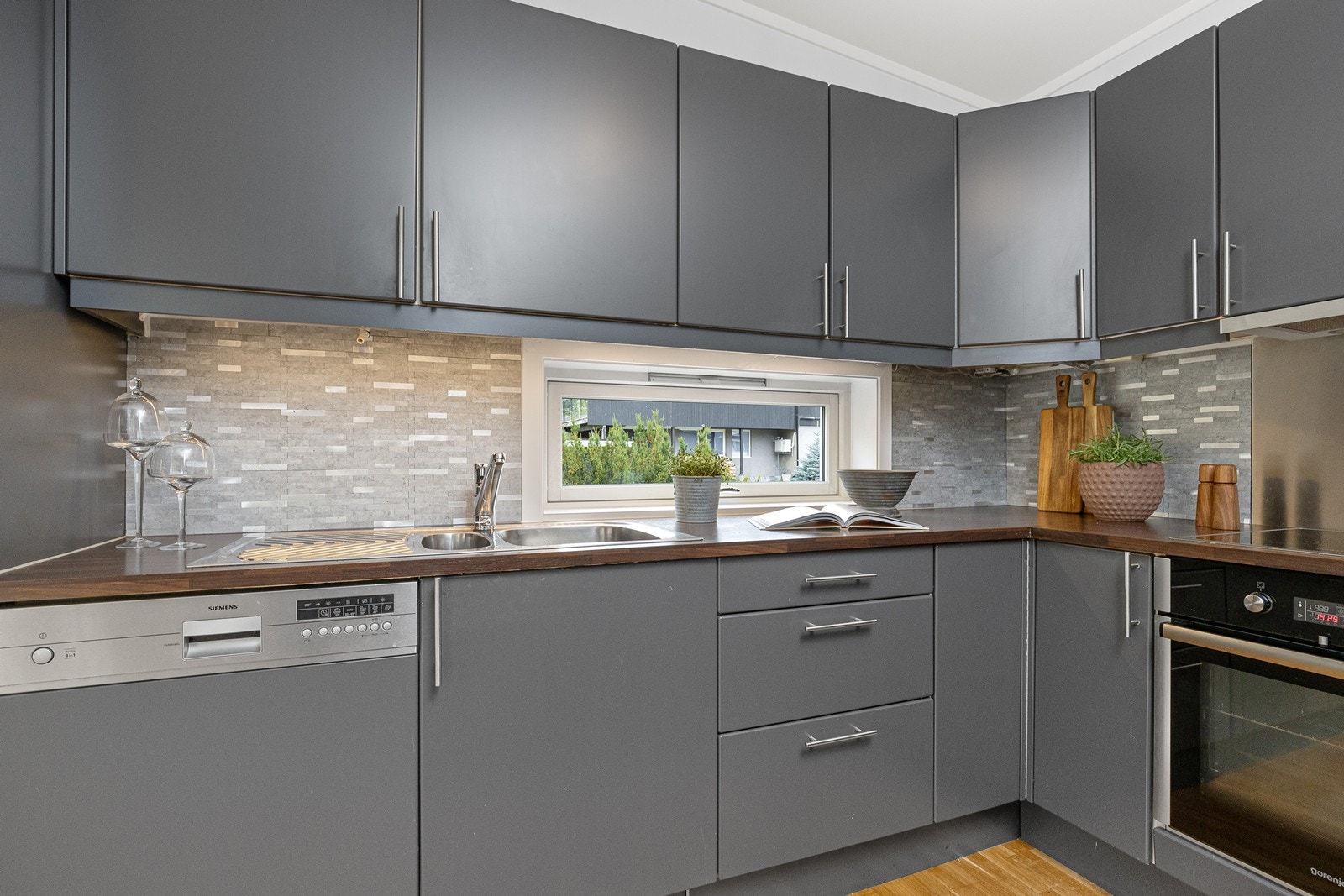 Fliser på vegg i forbindelse med innredningen, stålplate på vegg i kokesone og lys montert under overskap. Galleribilde