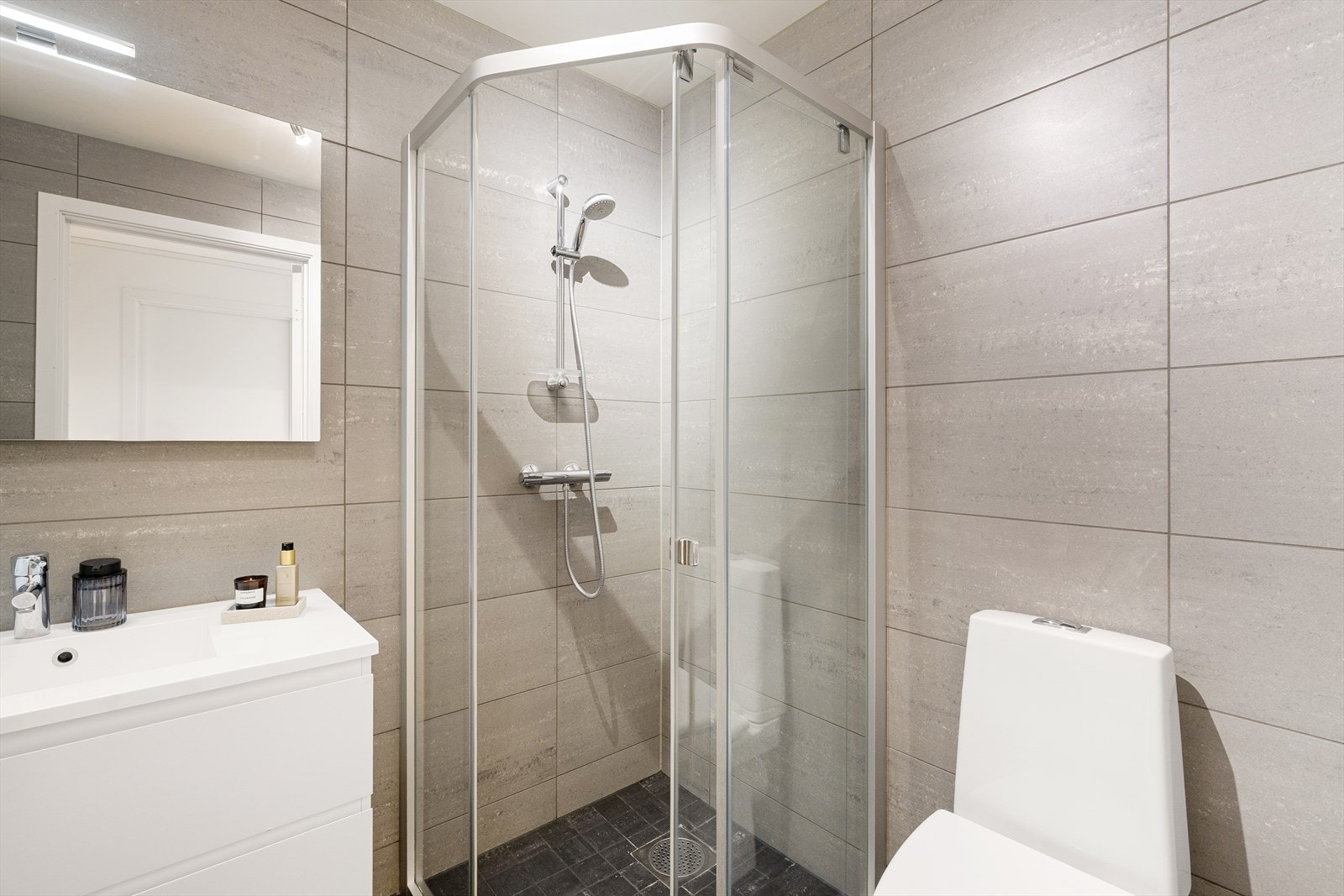 Badet i underetasjen er flislagt og har varme i gulv. Badet er innredet med vask i seksjon, dusj og toalett. Galleribilde