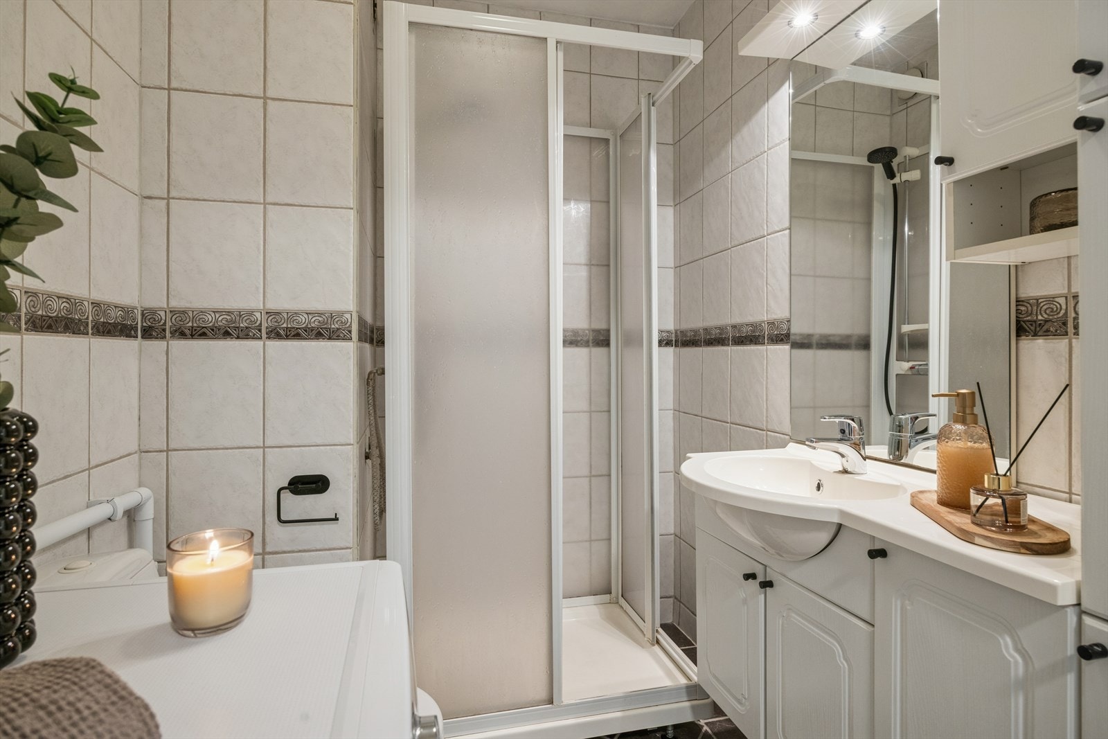 Helfliset bad med baderomsinnredning, dusjkabinett, wc og opplegg for vaskemaskin. Galleribilde