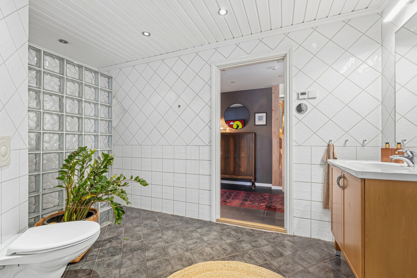 Badet i 1 etasje har tidløse flislagte vegger. Taket har panel. Det er innfelte downlights i
taket. Galleribilde