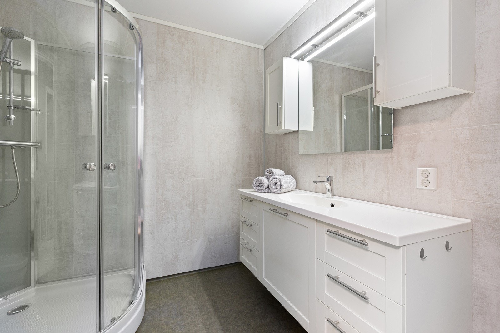 Lyst og trivelig baderom i første etasje innredet med baderomsservant, vegghengt toalett og dusjkabinett. Galleribilde