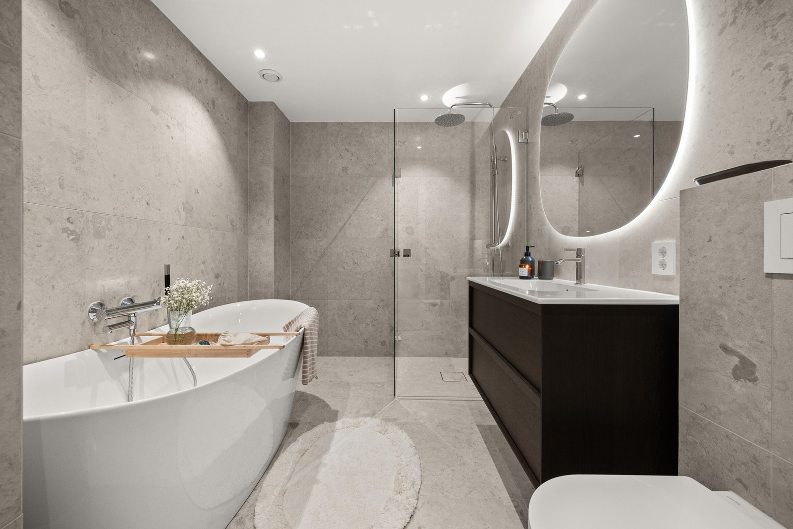 Nytt bad fra 2025/2026 med flislagte vegger og varmekabler i gulv. Badet er moderne og stilrent utformet, og inneholder badekar, dusjhjørne, vegghengt toalett samt speil med integrert belysning, og byr på høy komfort og god kvalitet. Galleribilde