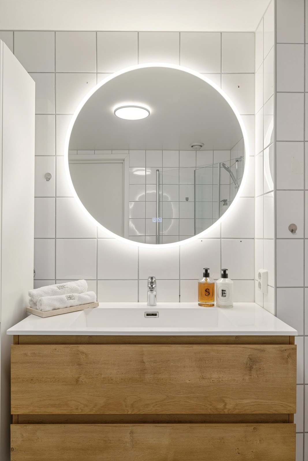 Flislagt bad med vegghengt klosett, dusjhjørne og opplegg for vaskesøyle. Galleribilde