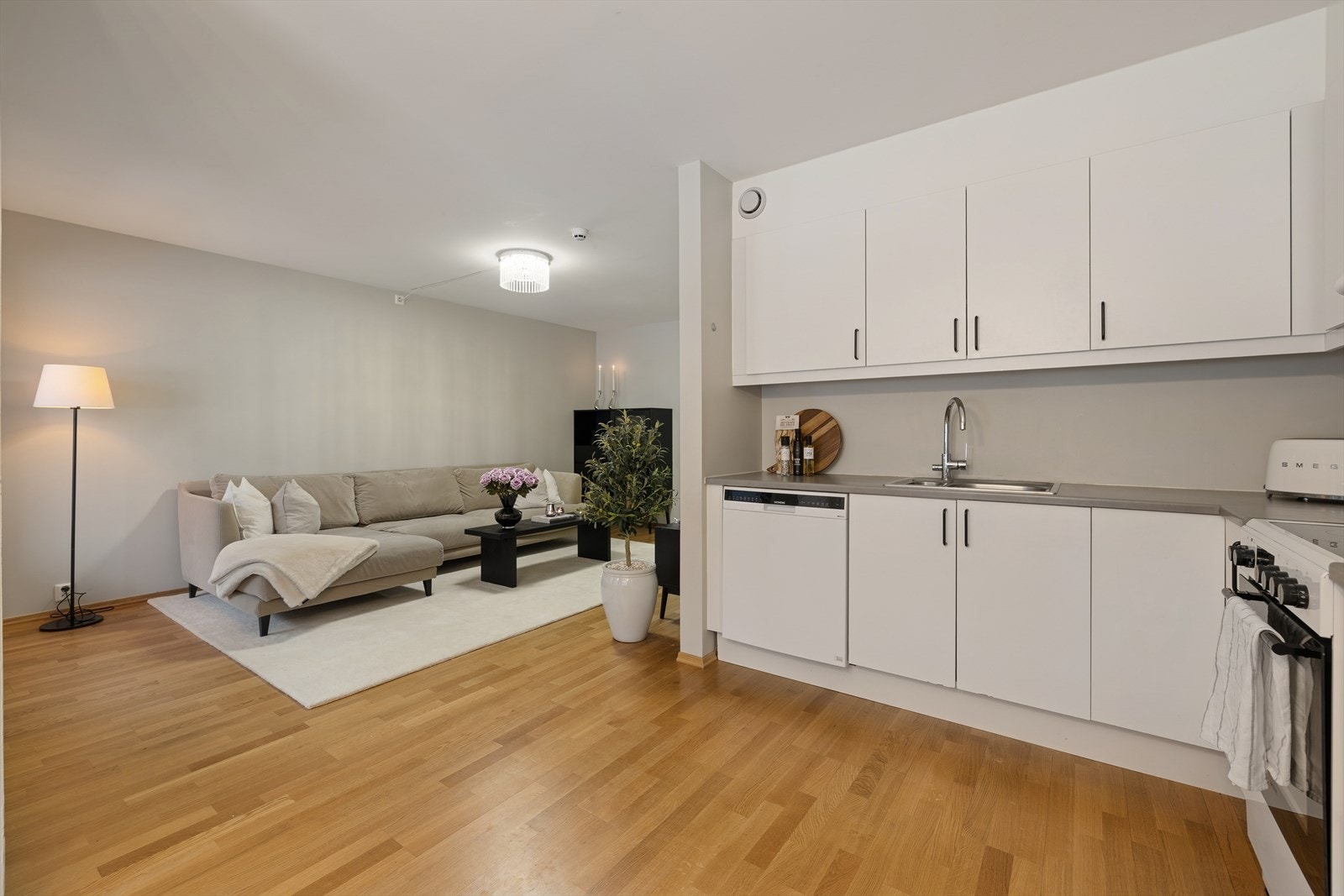 Kjøkkenet har tidløs innredning fra byggeåret med hvite, glatte fronter, laminat benkeplate med nedfelt kum i rustfritt stål. Galleribilde