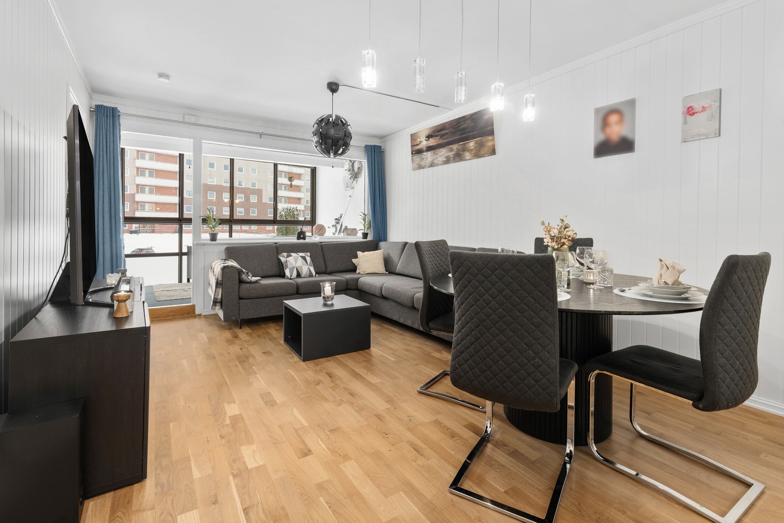 Lys stue med 3-stavs parkett på gulv, panel på vegger og slett flate i himling Galleribilde