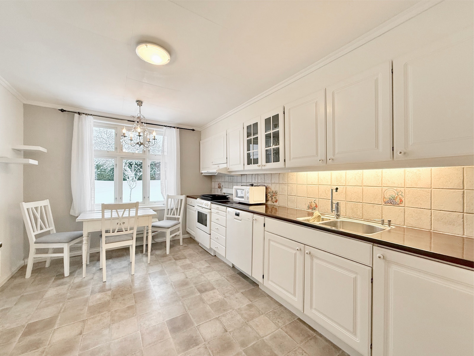 Kjøkkenet har hvite fronter, god benkeplass og spiseplass ved vinduet Galleribilde