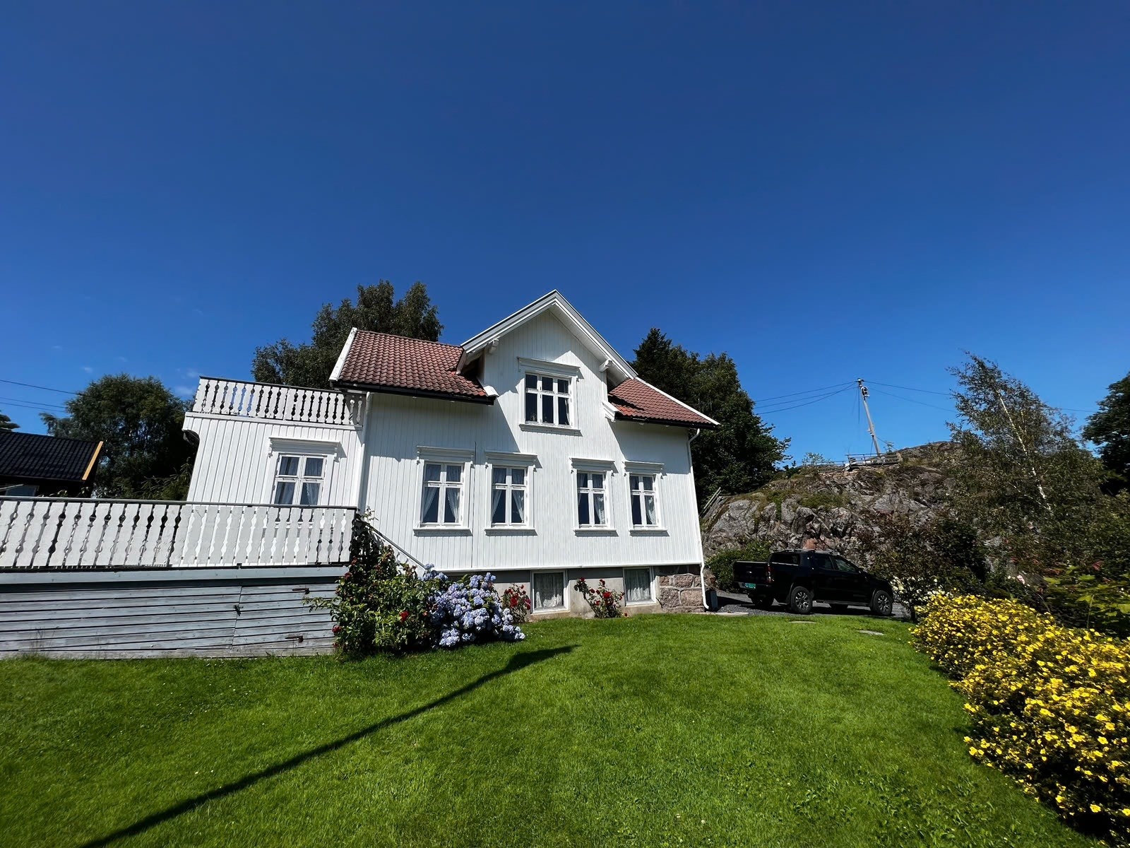 På sommeren fremstår huset idyllisk med plen, busker og fjellknauser rundt Galleribilde