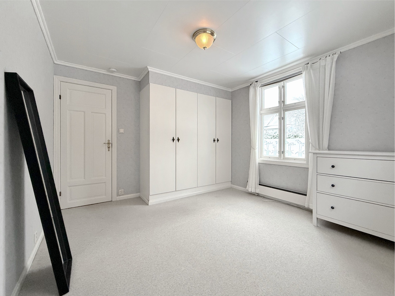 Hovedsoverom med god skapplass, lyse flater og vindu med gardiner Galleribilde