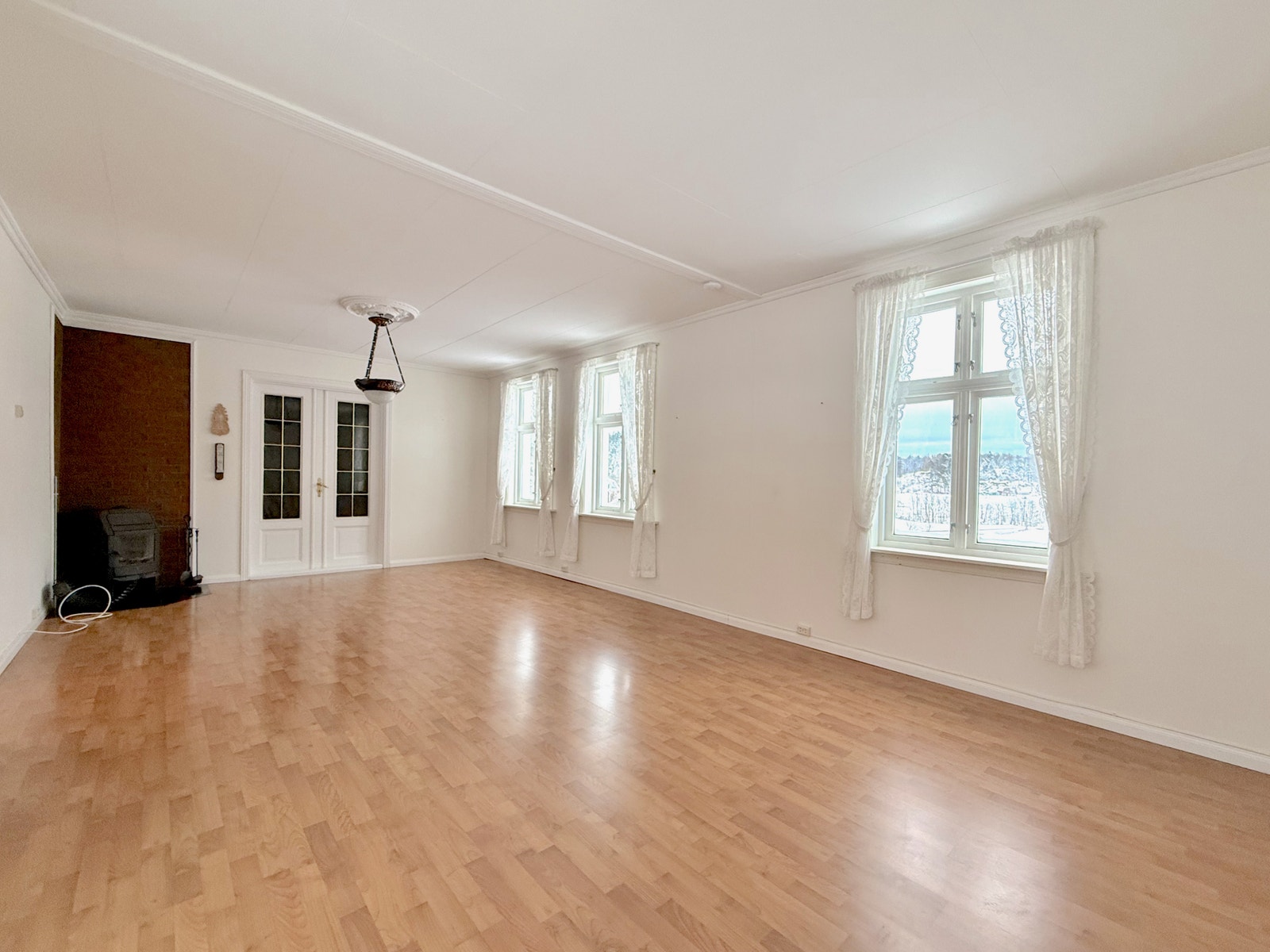 Stor stue med fint gulv, klassiske dører og peis i hjørnet Galleribilde