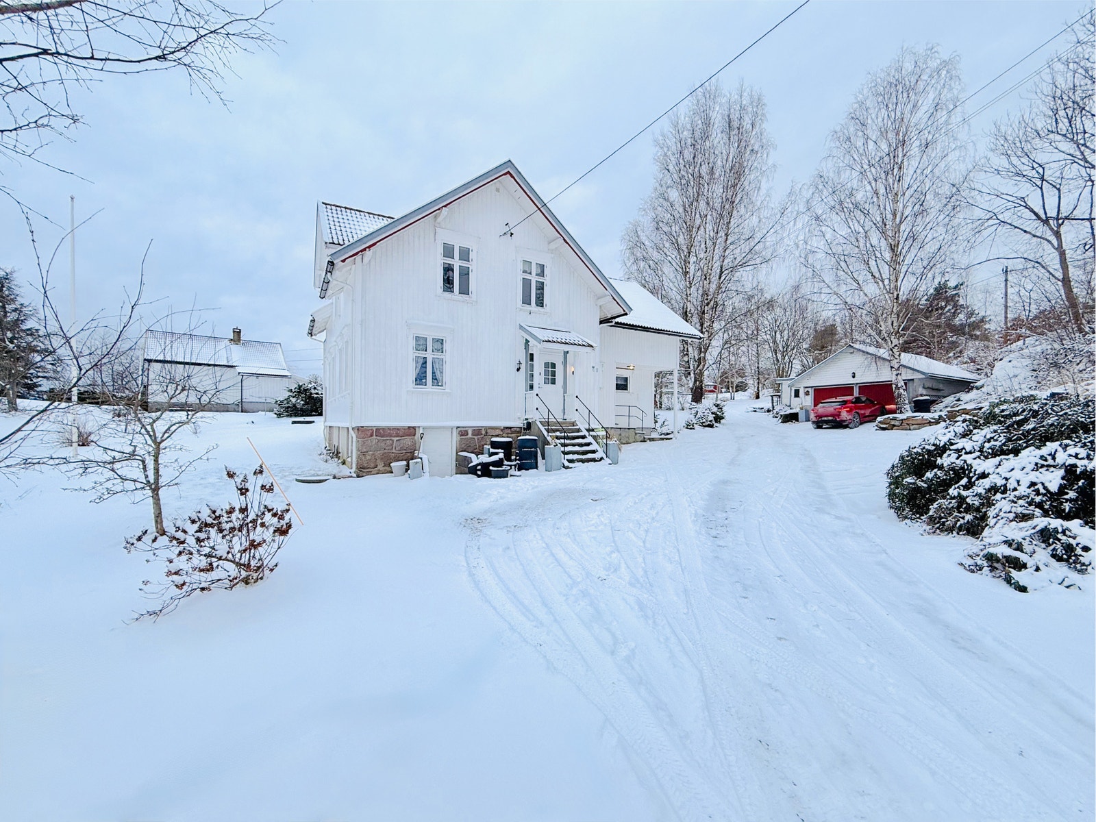 Fasaden av eneboligen med oppkjørsel og snødekte uteområder Galleribilde