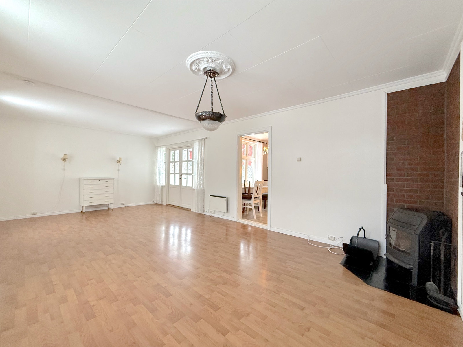 Vedovnen mot murvegg gir ekstra varme til den lyse stuen Galleribilde