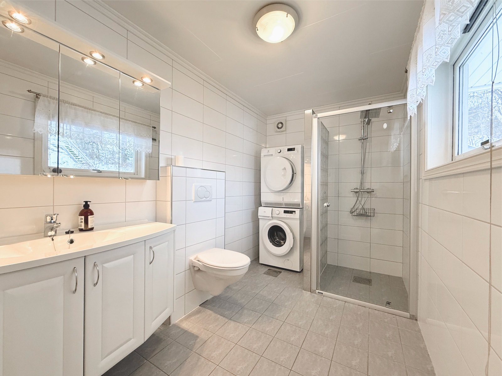 Badet har dusjnisje med glassvegg samt vaskemaskin og tørketrommel Galleribilde