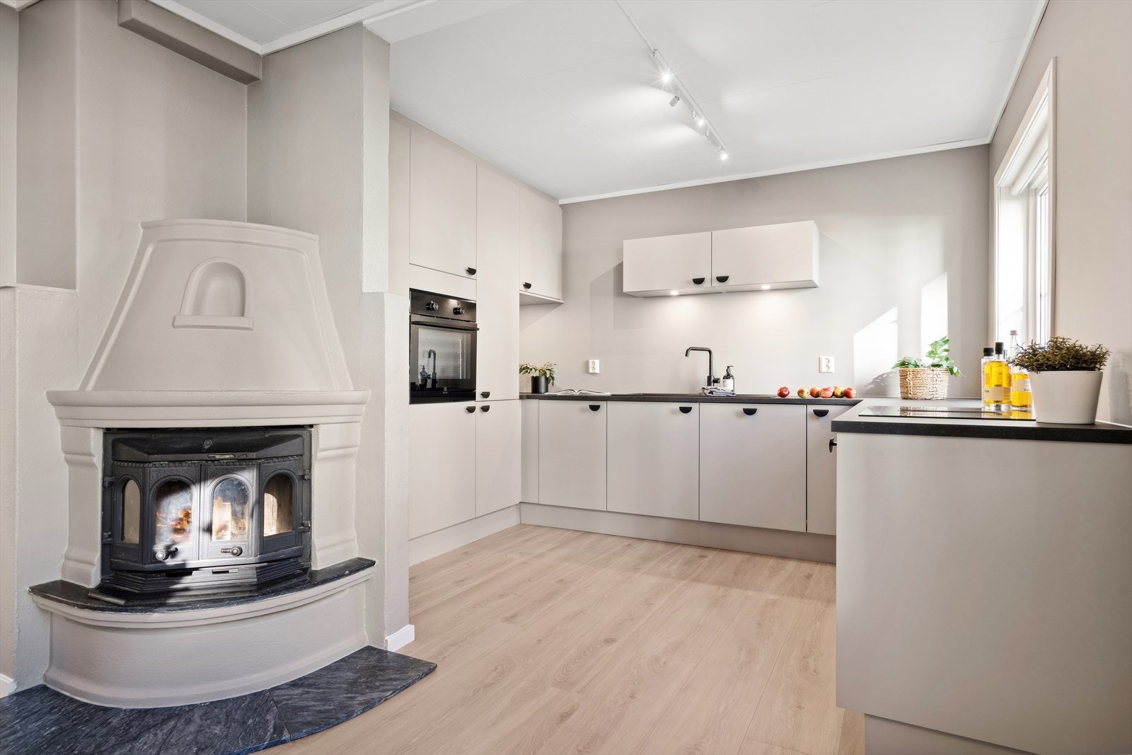 Kjøkkenet har en stilren innredning av nyere dato med malte slette fronter og laminat benkeplate med nedfelt kjøkkenvask - Her det det benyttet sorte detaljer på bl.a. dørhåndtak, servant og blandebatteri Galleribilde