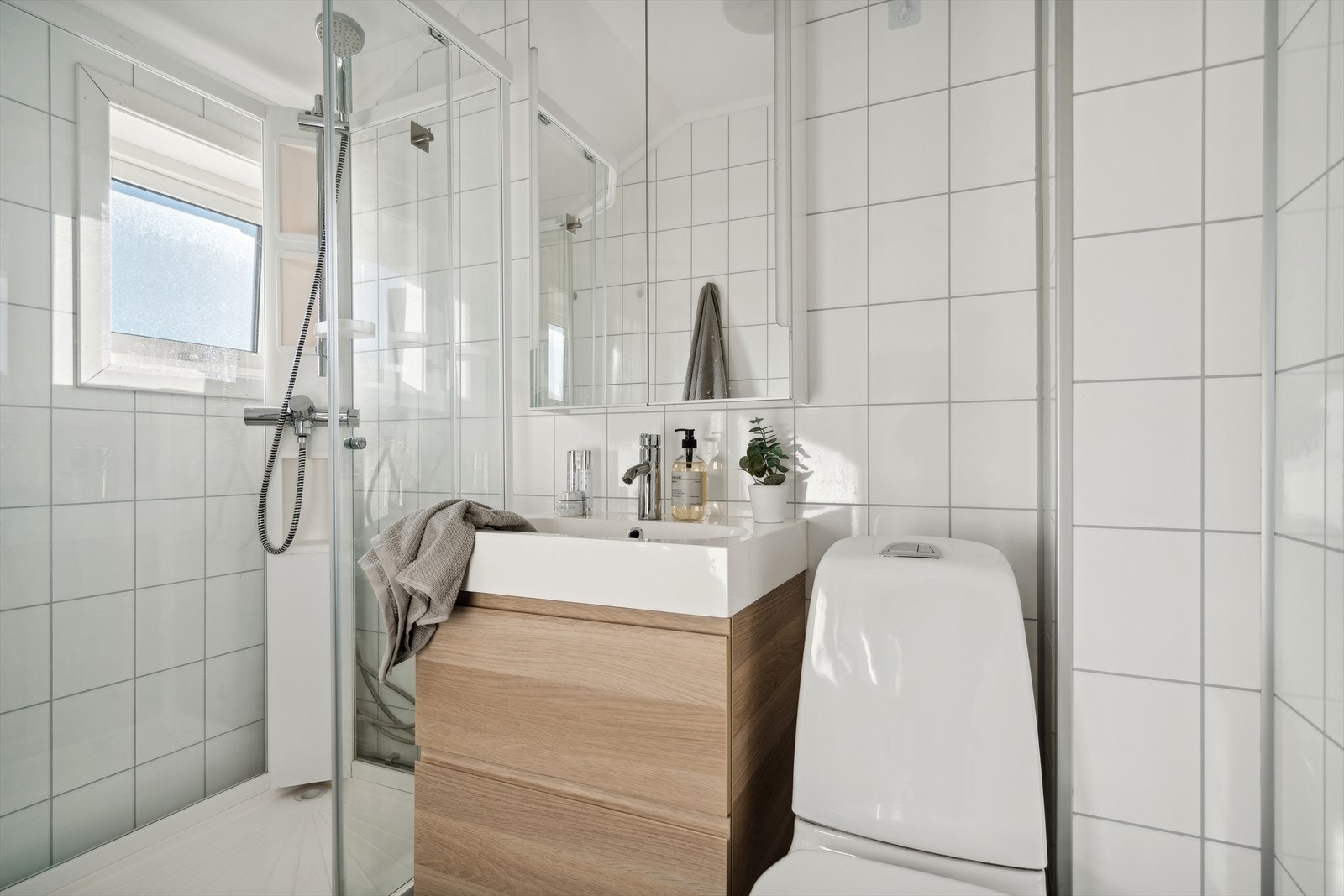 Her finner du toalett, dusjkabinett, servantinnredning med skuffer under og overskap med speilfronter Galleribilde