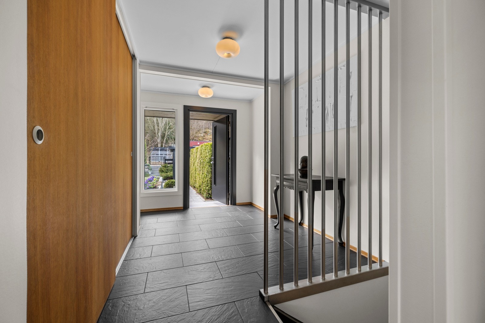 Entreen har en skyvedørsgarderobe med fronter eik, samt stilige spiler i børstet stål som gir et moderne inntrykk Galleribilde