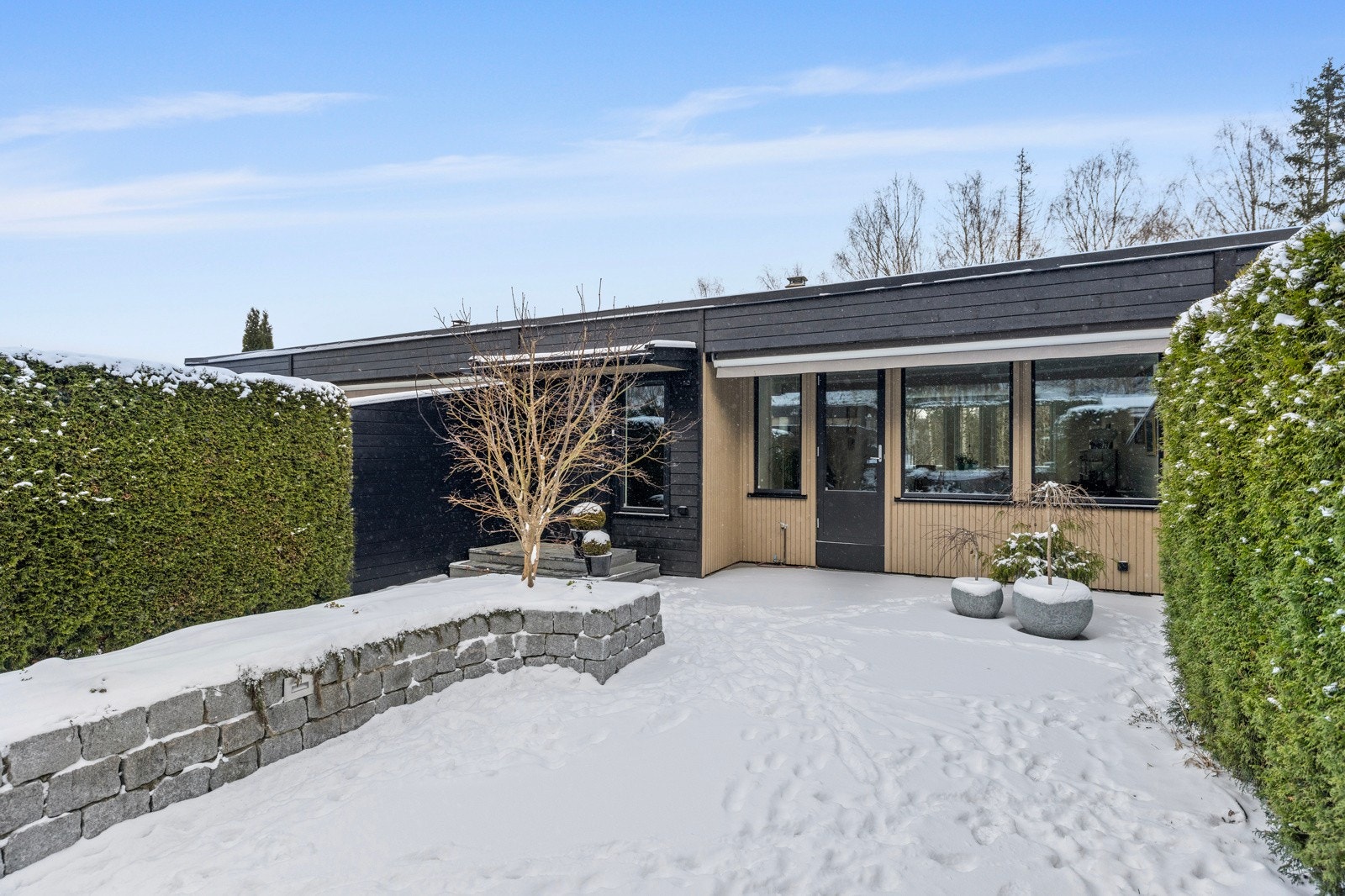 Rundt inngangen står det busker som rammer inn området på en naturlig måte Galleribilde