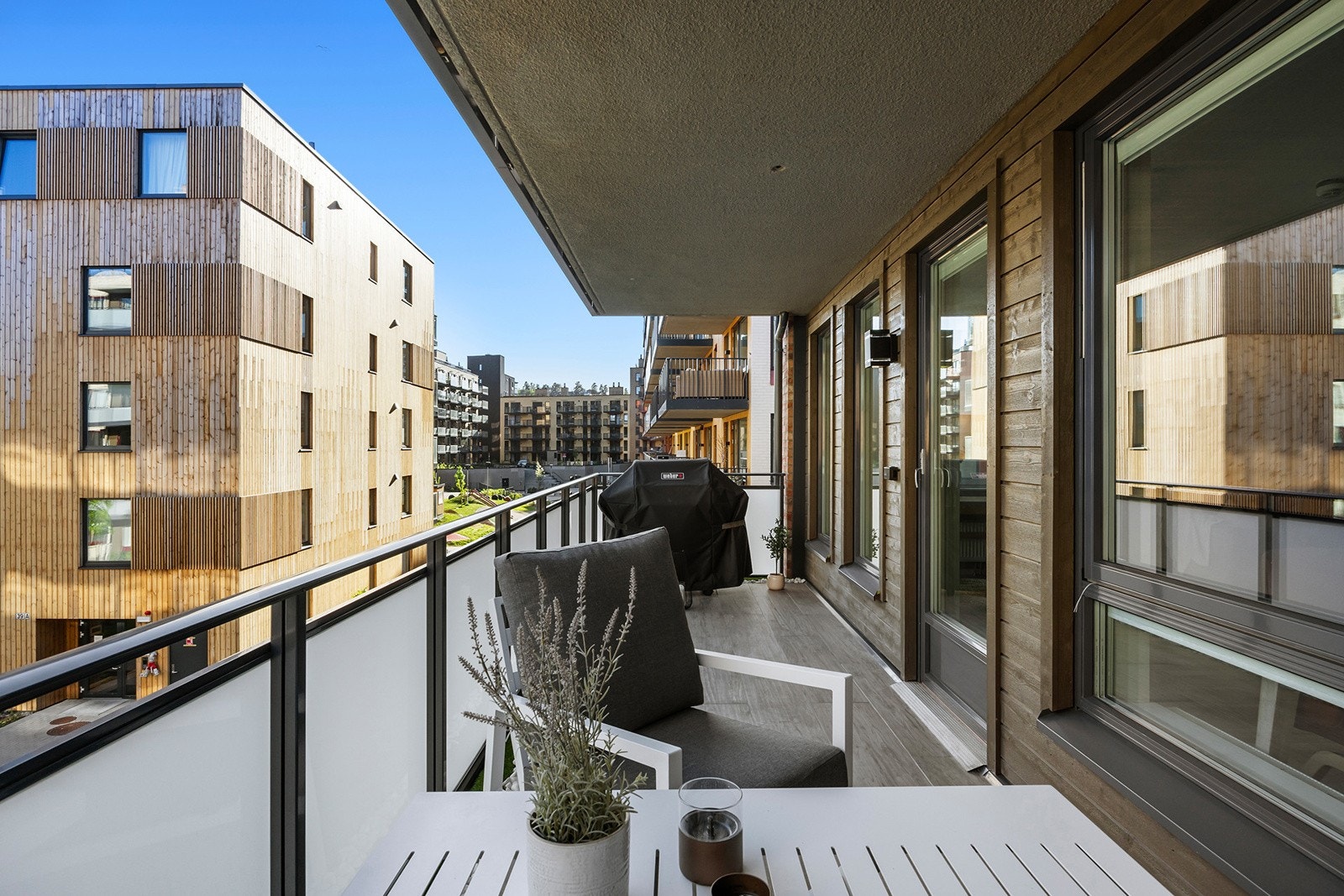 Balkongen har flislagt gulv, liggende panel på yttervegg mot stue, utelys, dobbel stikkontakt og rekkverk av glass/stål. Galleribilde