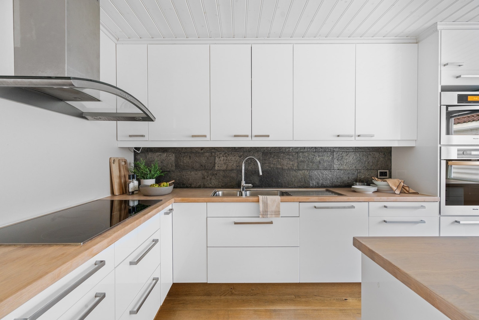 Fliser på vegg mellom overskap og benk.
Enstavsparkett på gulv. Et meget kjekt rom. Galleribilde