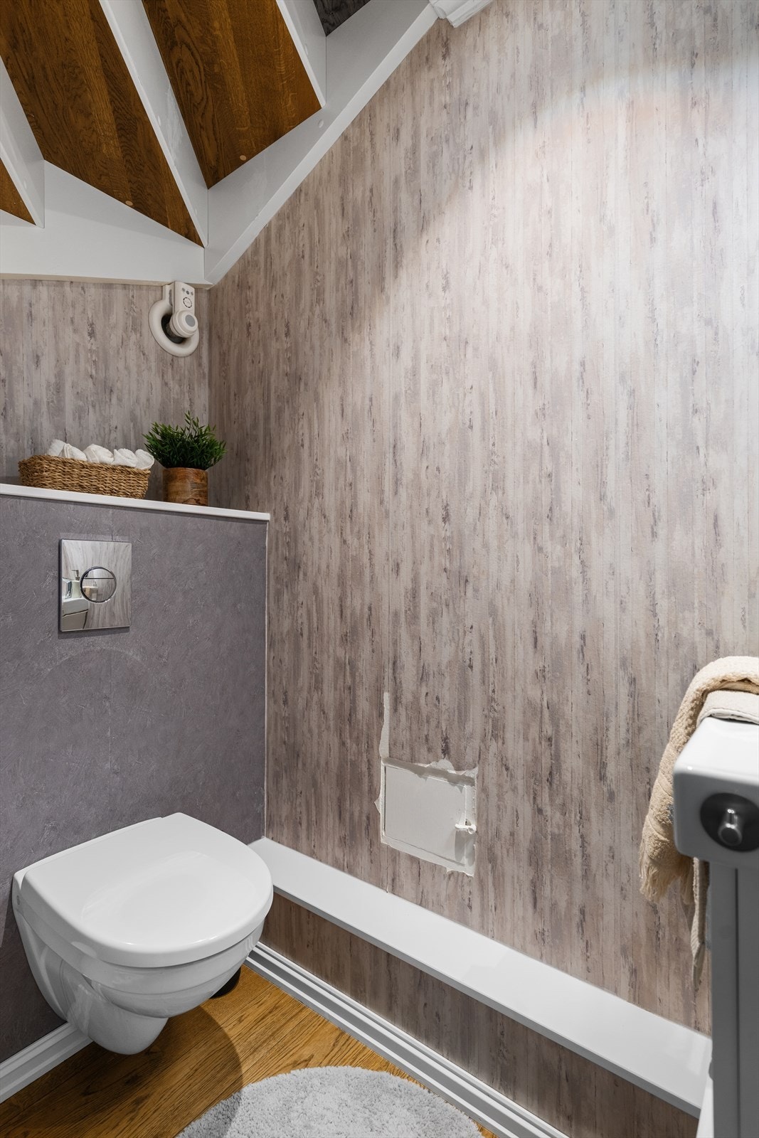 Gjestewc ligger ved entré og har parkett på gulv, vegghengt toalett, tapet på vegg og enkel servant. Galleribilde