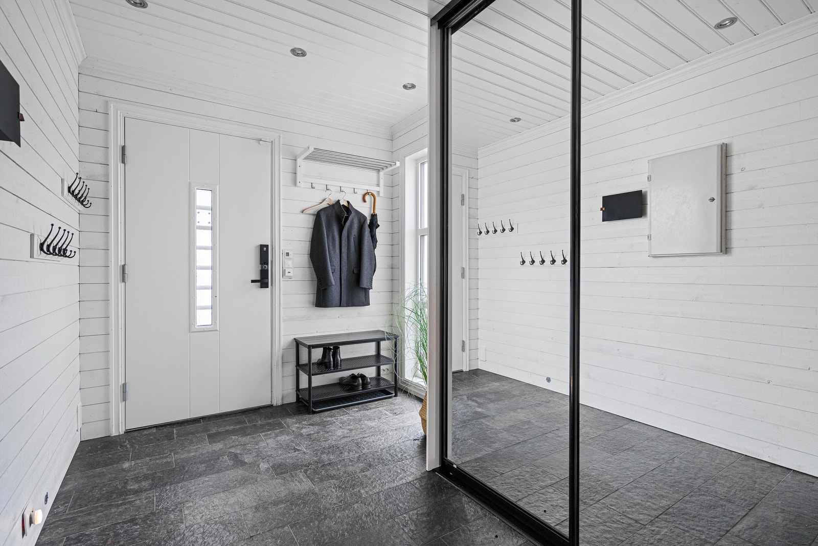 Entré med skiferfliser på gulv, vegger med lyst panel og spotter i tak. Entré er romslig og har plass til f.eks en barnevogn inne, dersom man skulle trenge det. Galleribilde