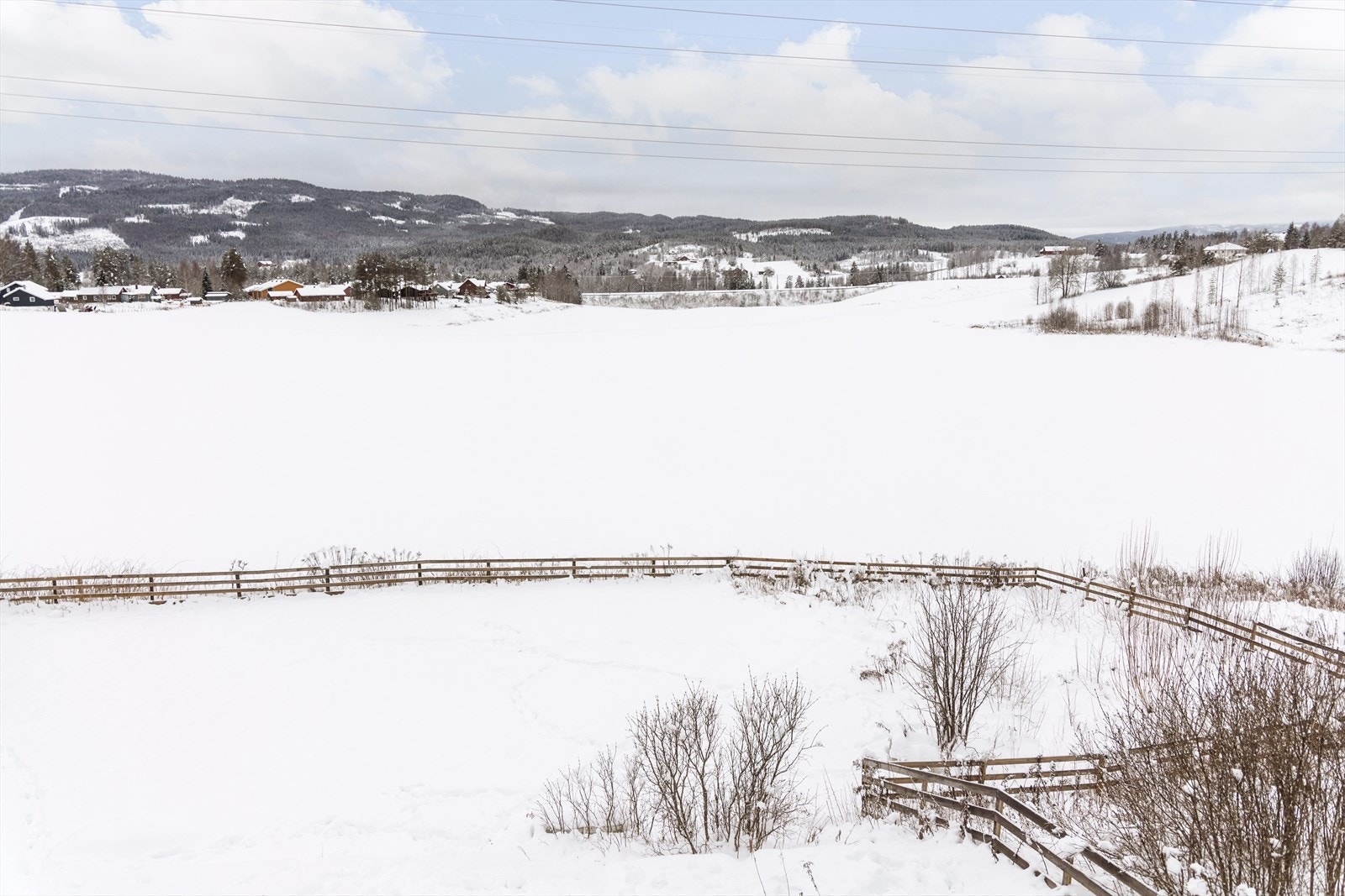 Fra eiendommen er det en åpen utsikt over det omkringliggende kulturlandskapet med skiløyper på jordet om vinteren. Galleribilde
